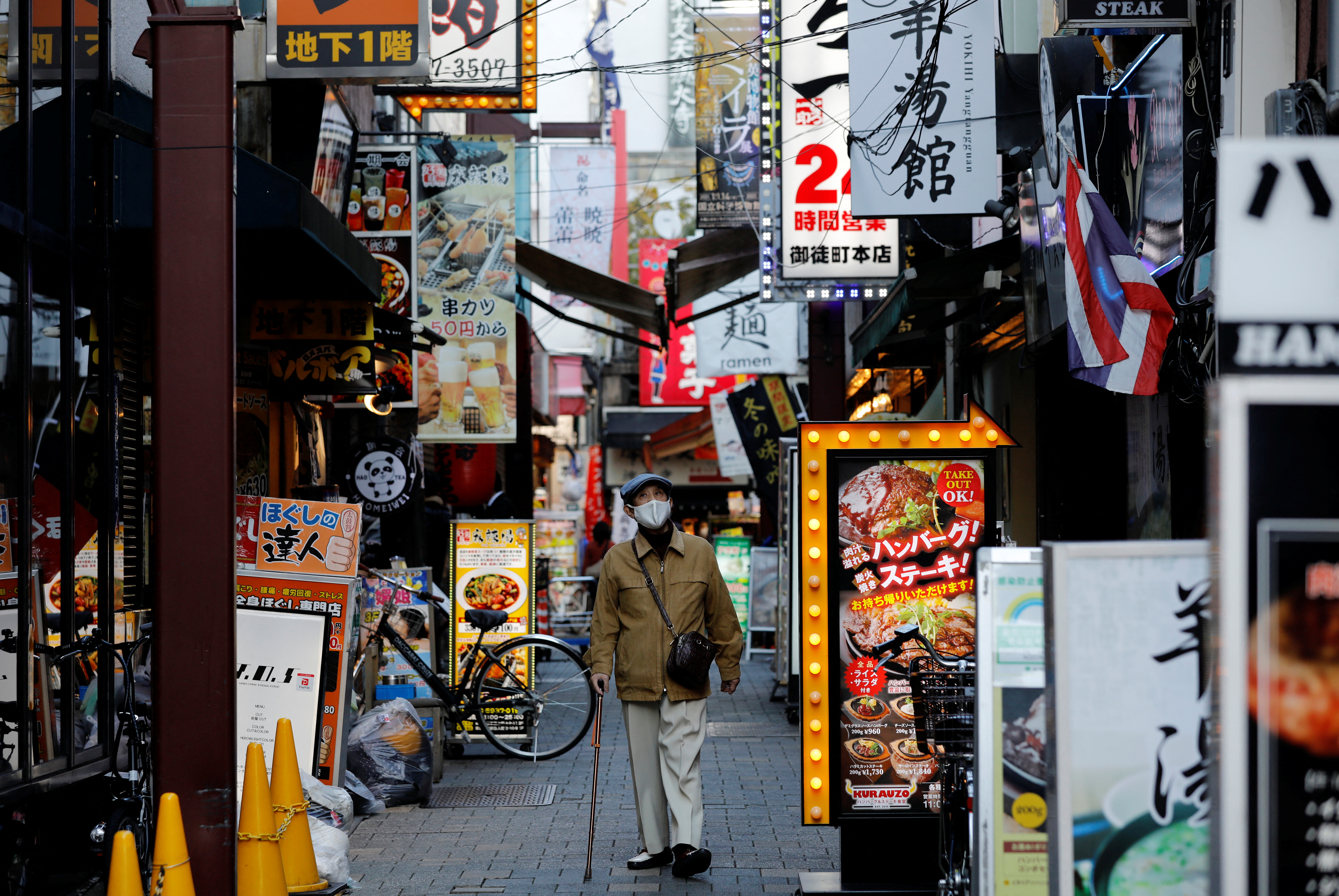 A man wearing a protective mask, amid the coronavirus disease (COVID-19) outbreak, makes his way at a restaurant district in Tokyo
