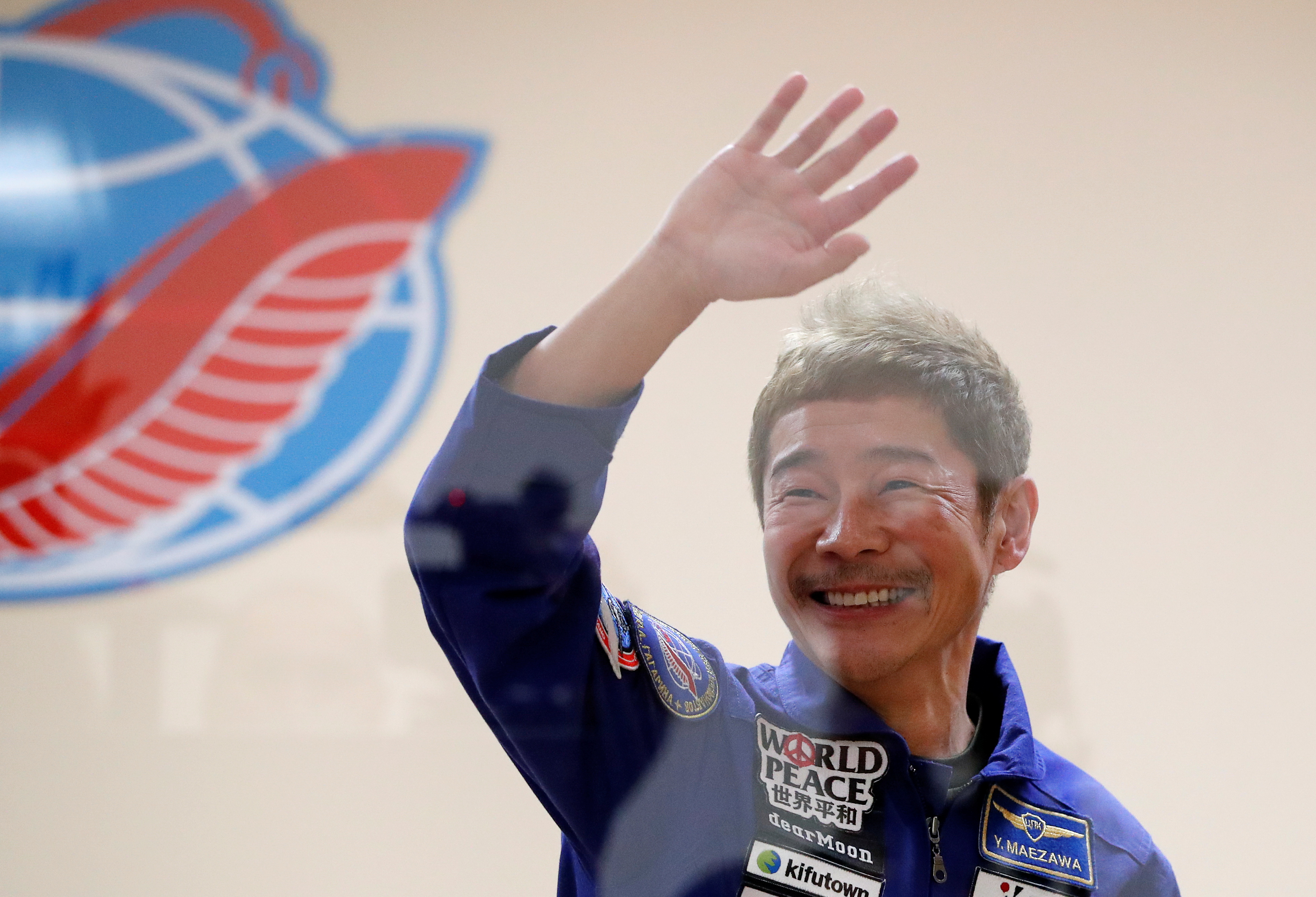 Japanese entrepreneur and space flight participant Yusaku Maezawa waves behind a glass wall during a news conference in Baikonur, Kazakhstan December 7, 2021. Maezawa, Roscosmos cosmonaut Alexander Misurkin and flight participant Yozo Hirano take part in a mission to the International Space Station (ISS) scheduled for December 8, 2021. REUTERS/Shamil Zhumatov/Pool