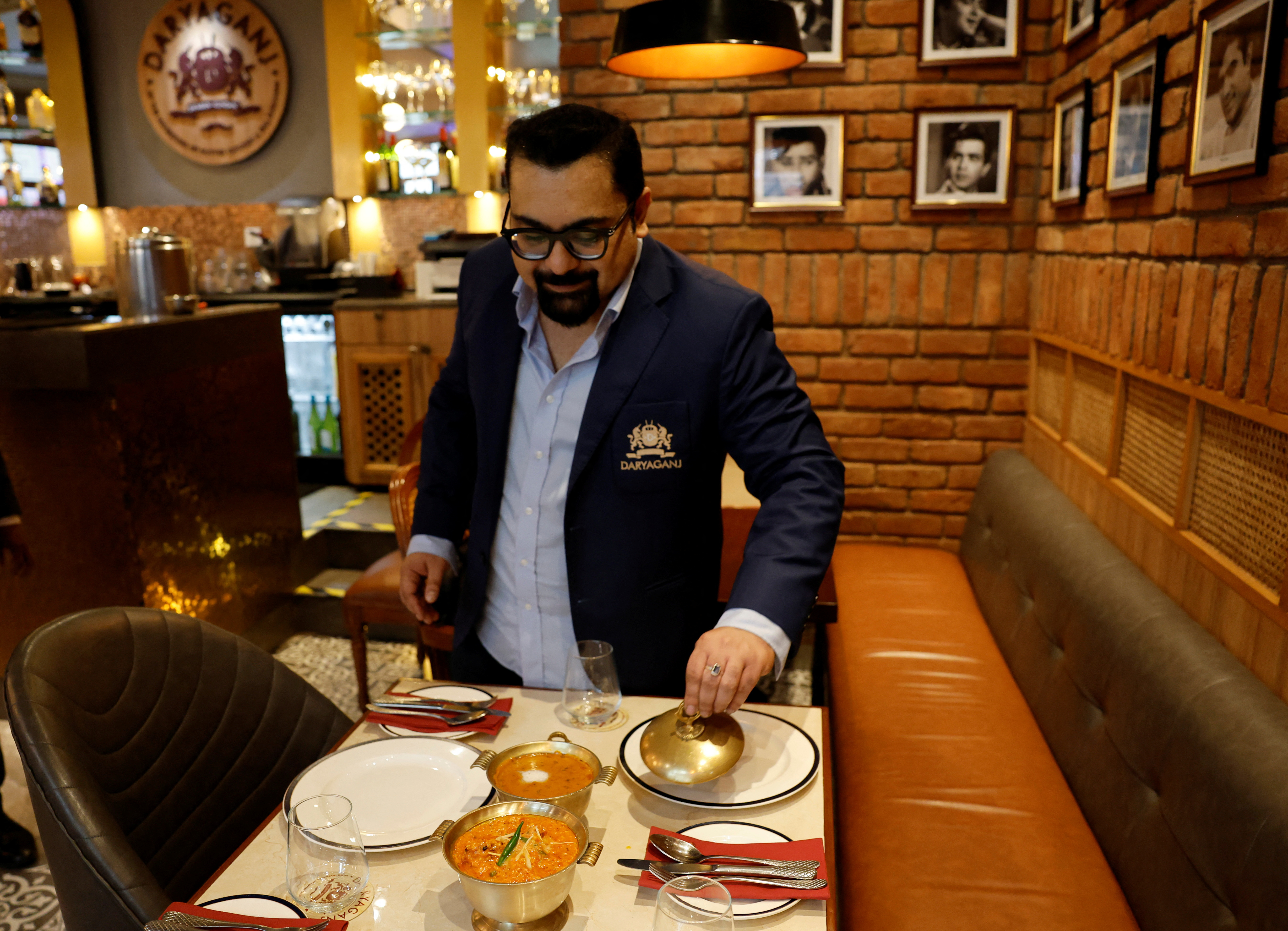Amit Bagga, CEO of Daryaganj restaurant, shows a freshly prepared butter chicken dish and the lentil dish Dal Makhani, inside Daryaganj restaurant at a mall, in Noida