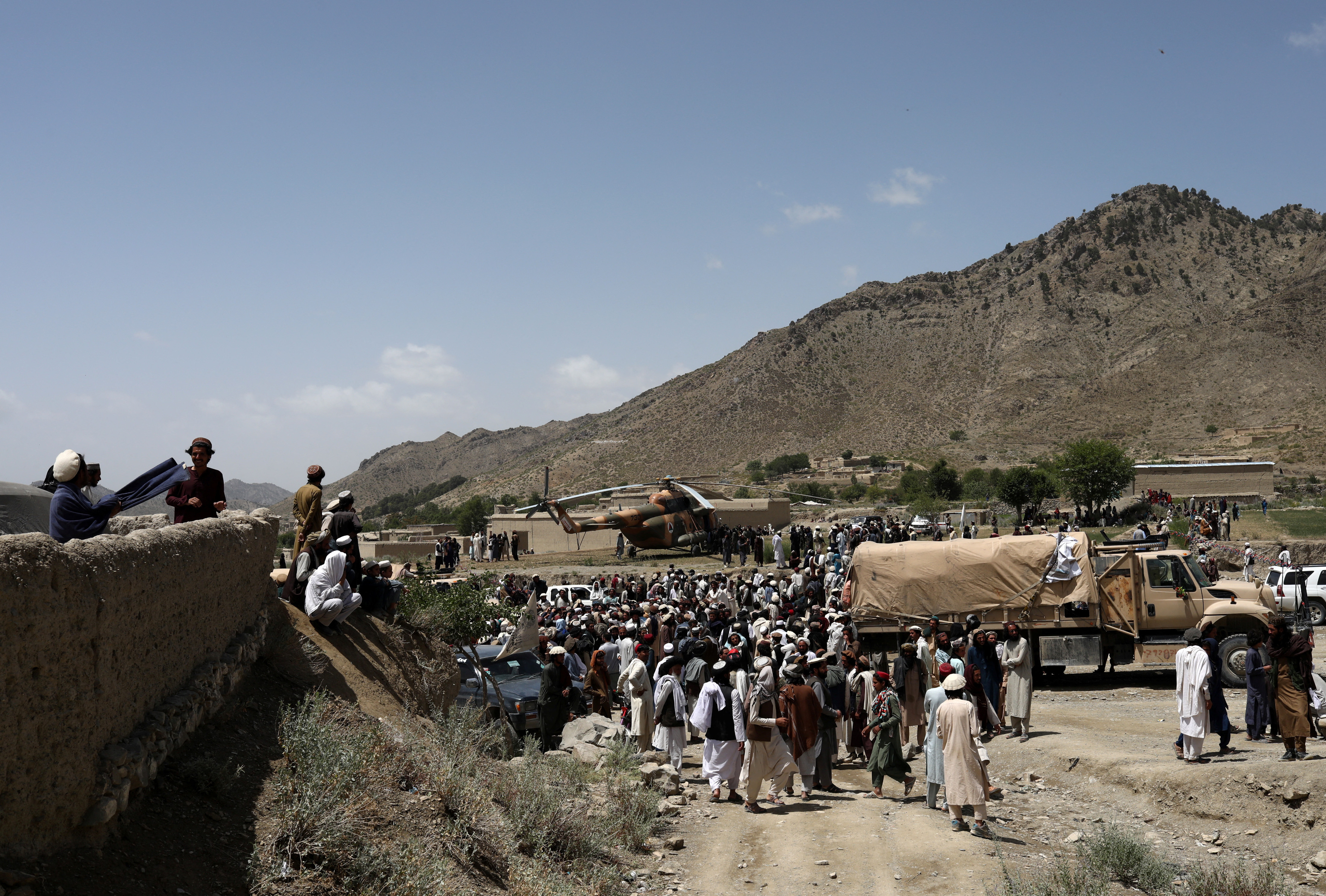 Afghan people wait to receive aid in an area affected by an earthquake in Gayan