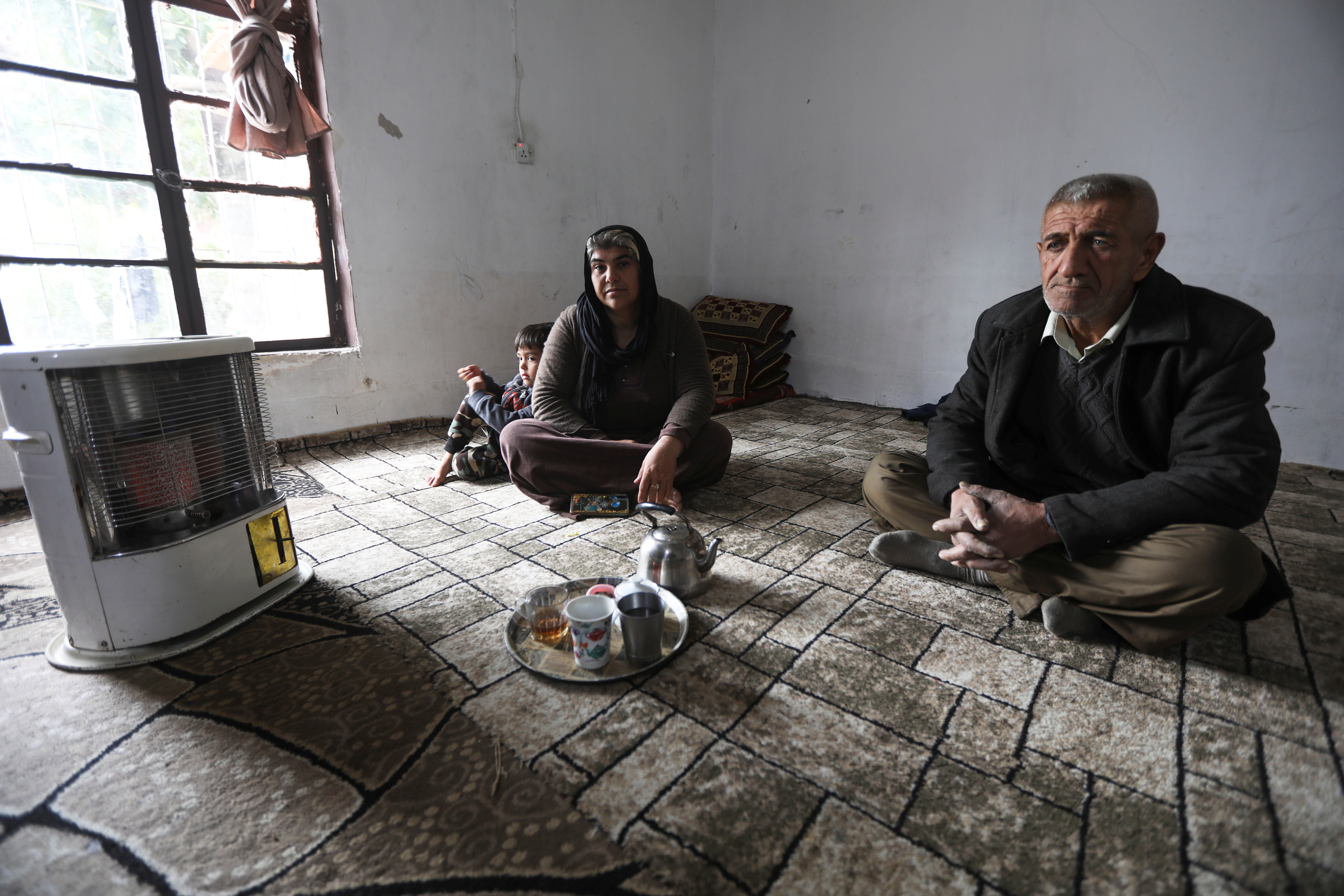 Zarin Soleiman, an Iranian Kurdish woman, sits with her brother after her son went to Minsk, in Qaladize