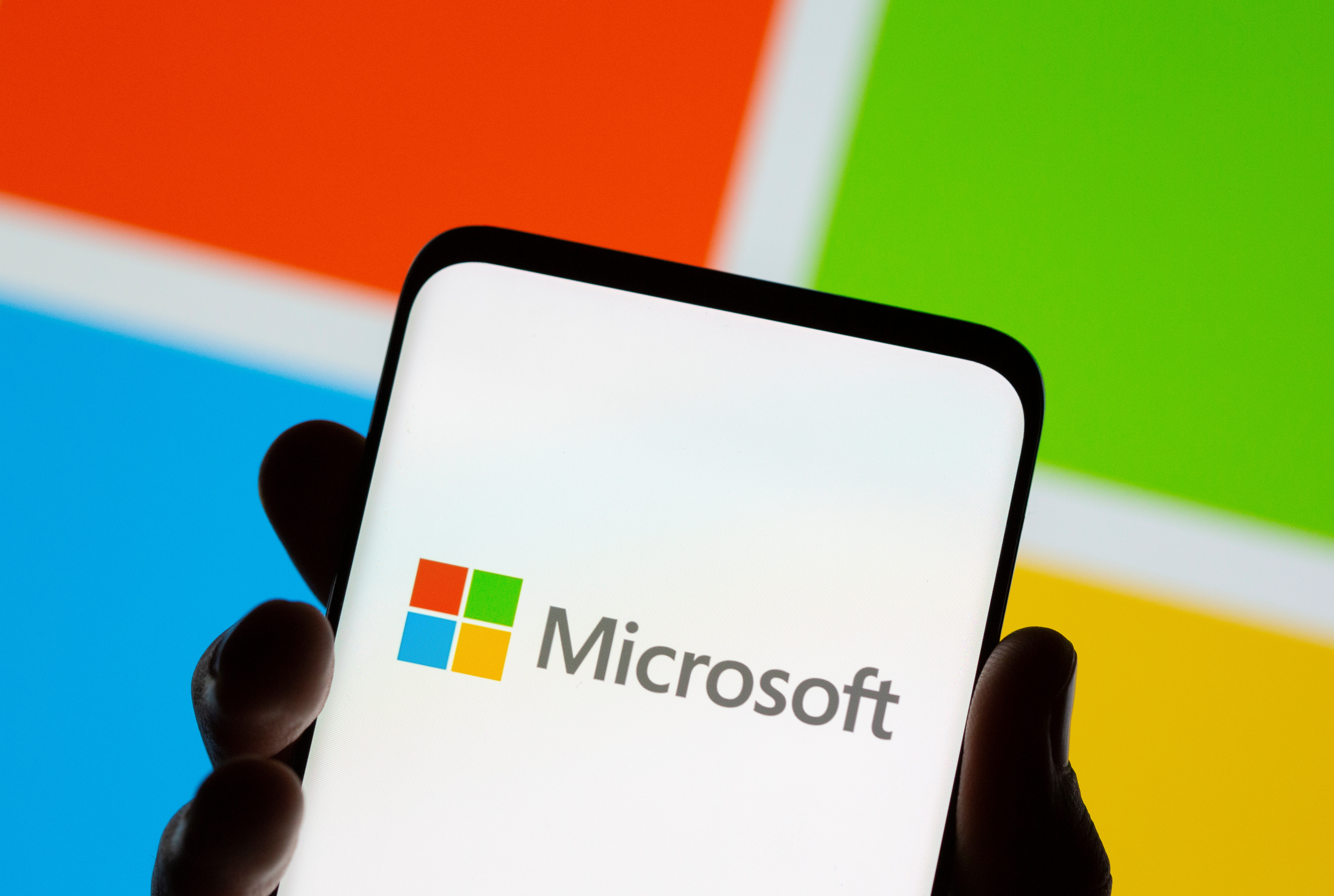 El teléfono inteligente se ve frente al logotipo de Microsoft que se muestra en esta ilustración tomada