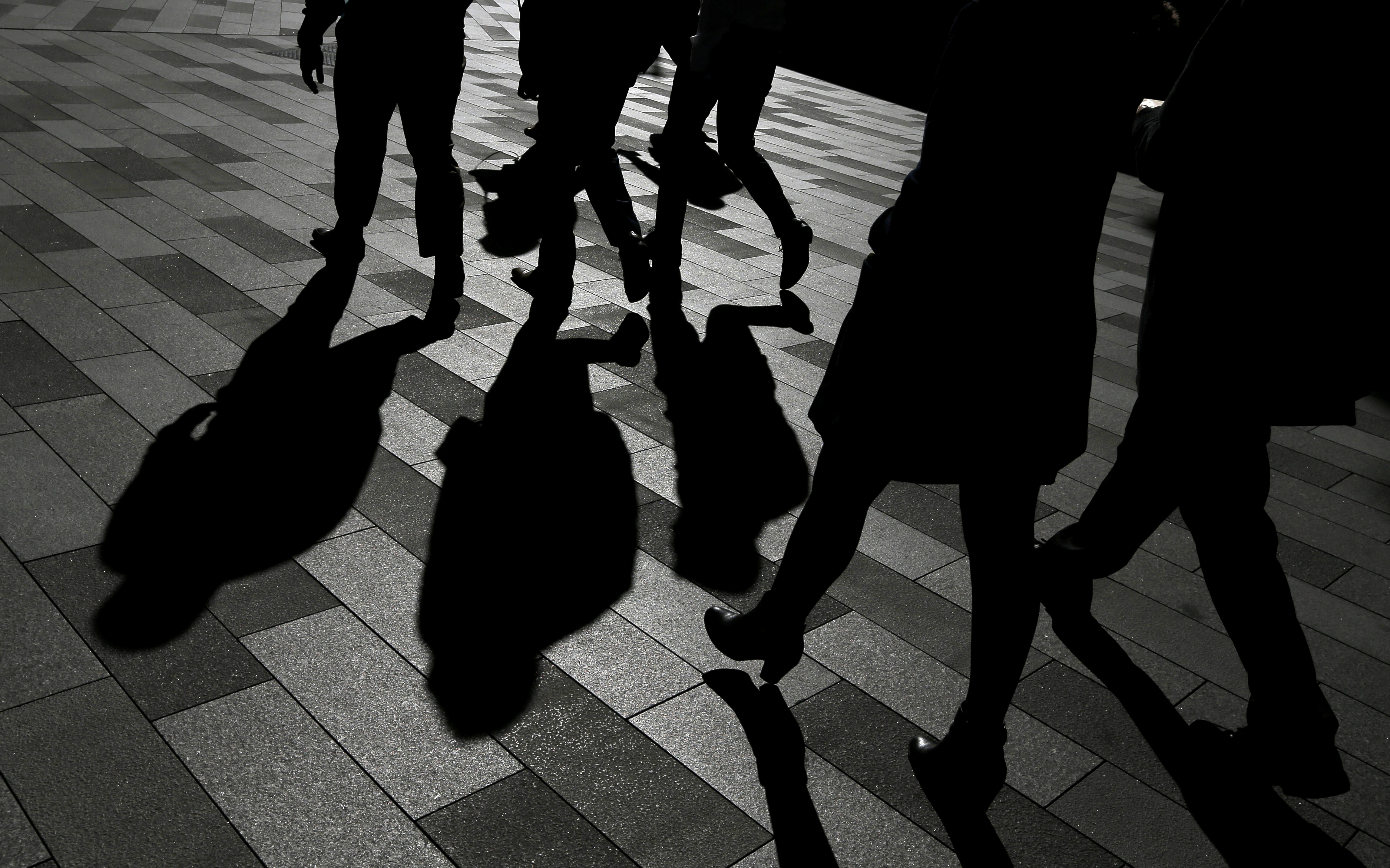 Workers cast shadows as they stroll among the office towers Sydney's Barangaroo business district in Australia's largest city