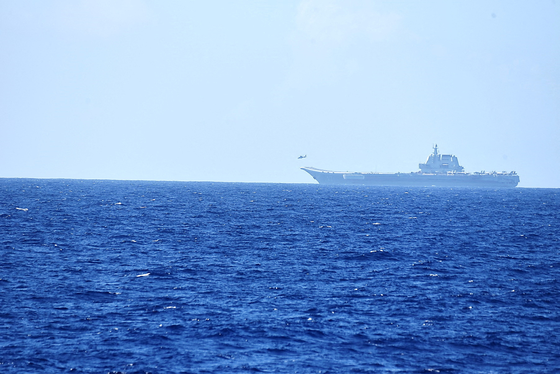 A helicopter takes off from China's Shandong aircraft carrier, over Pacific Ocean waters, south of Okinawa prefecture