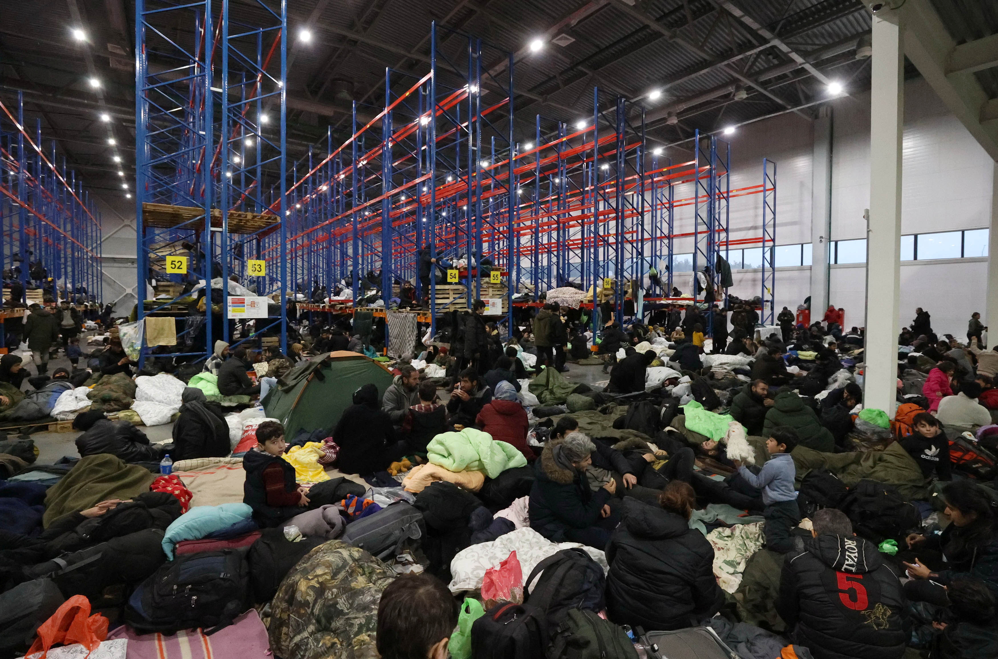 Migrants stay in the transport and logistics centre Bruzgi on the Belarusian-Polish border in the Grodno region, Belarus November 19, 2021.  Maxim Guchek/BelTA/Handout via REUTERS ATTENTION EDITORS - THIS IMAGE HAS BEEN SUPPLIED BY A THIRD PARTY. NO RESALES. NO ARCHIVES. MANDATORY CREDIT.