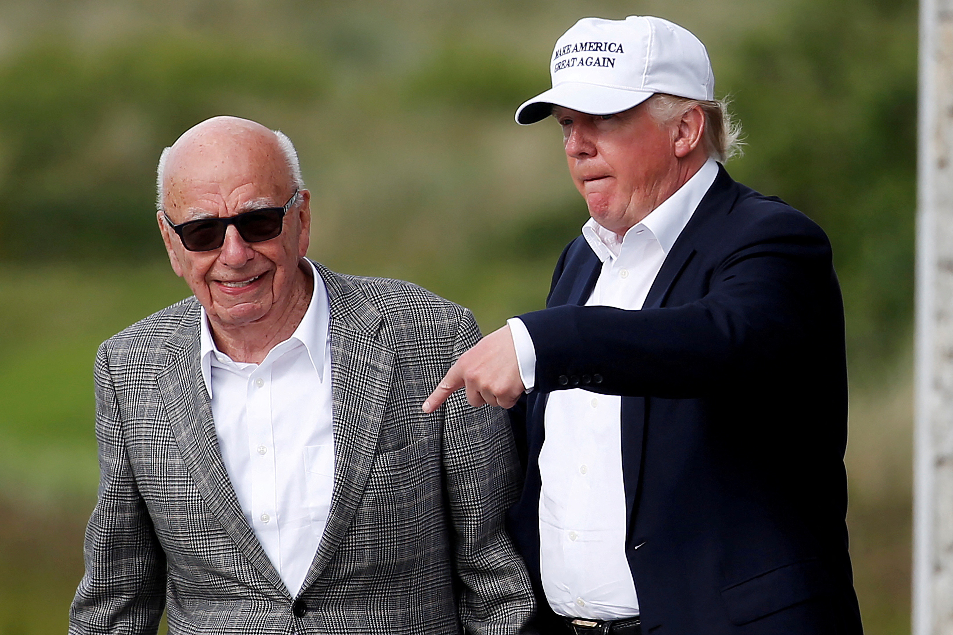 Republican presidential candidate Donald Trump speaks to media mogul Rupert Murdoch as they walk out of Trump International Golf Links in Aberdeen