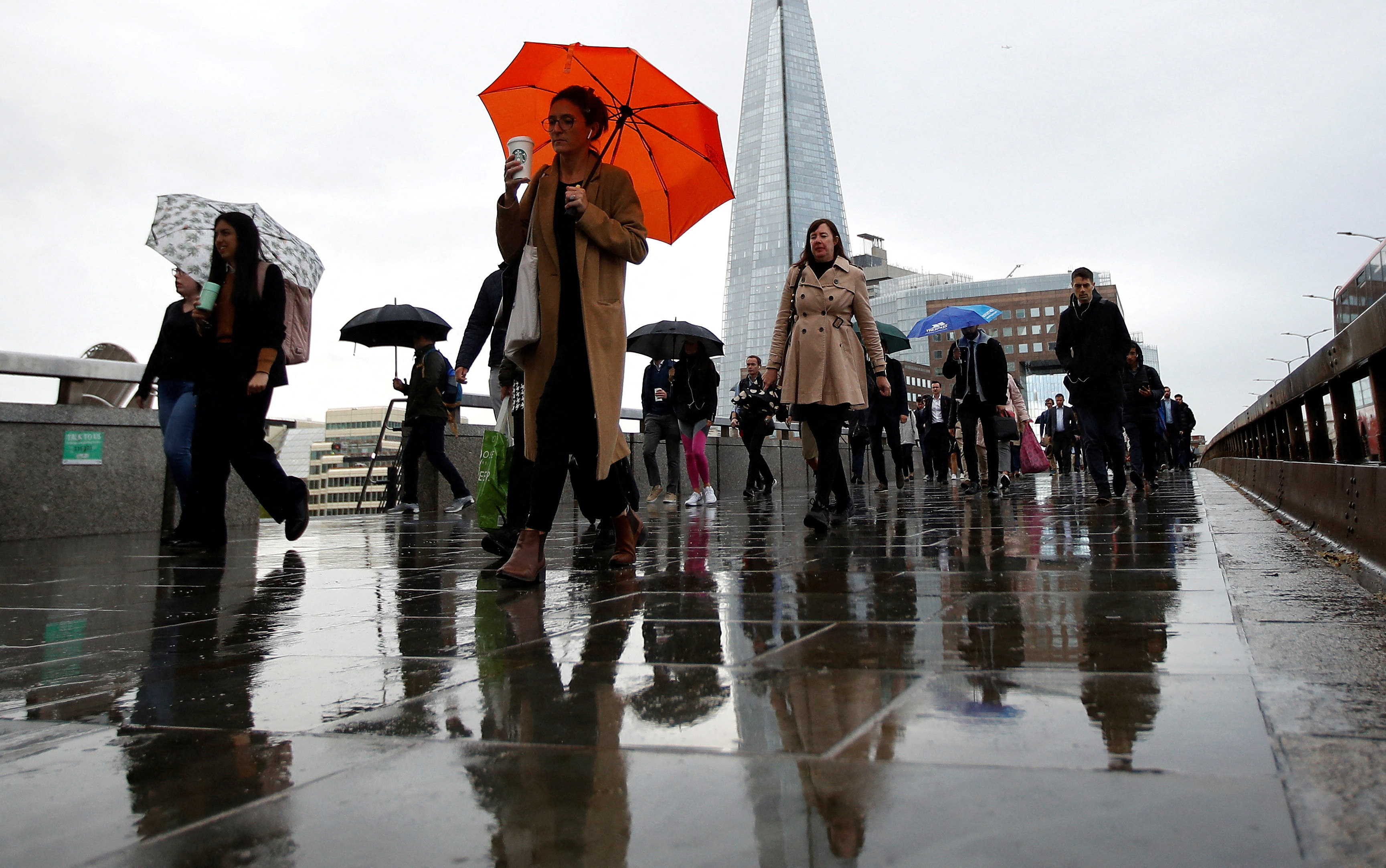Commuters walk across London Bridge toward the financial district, in London