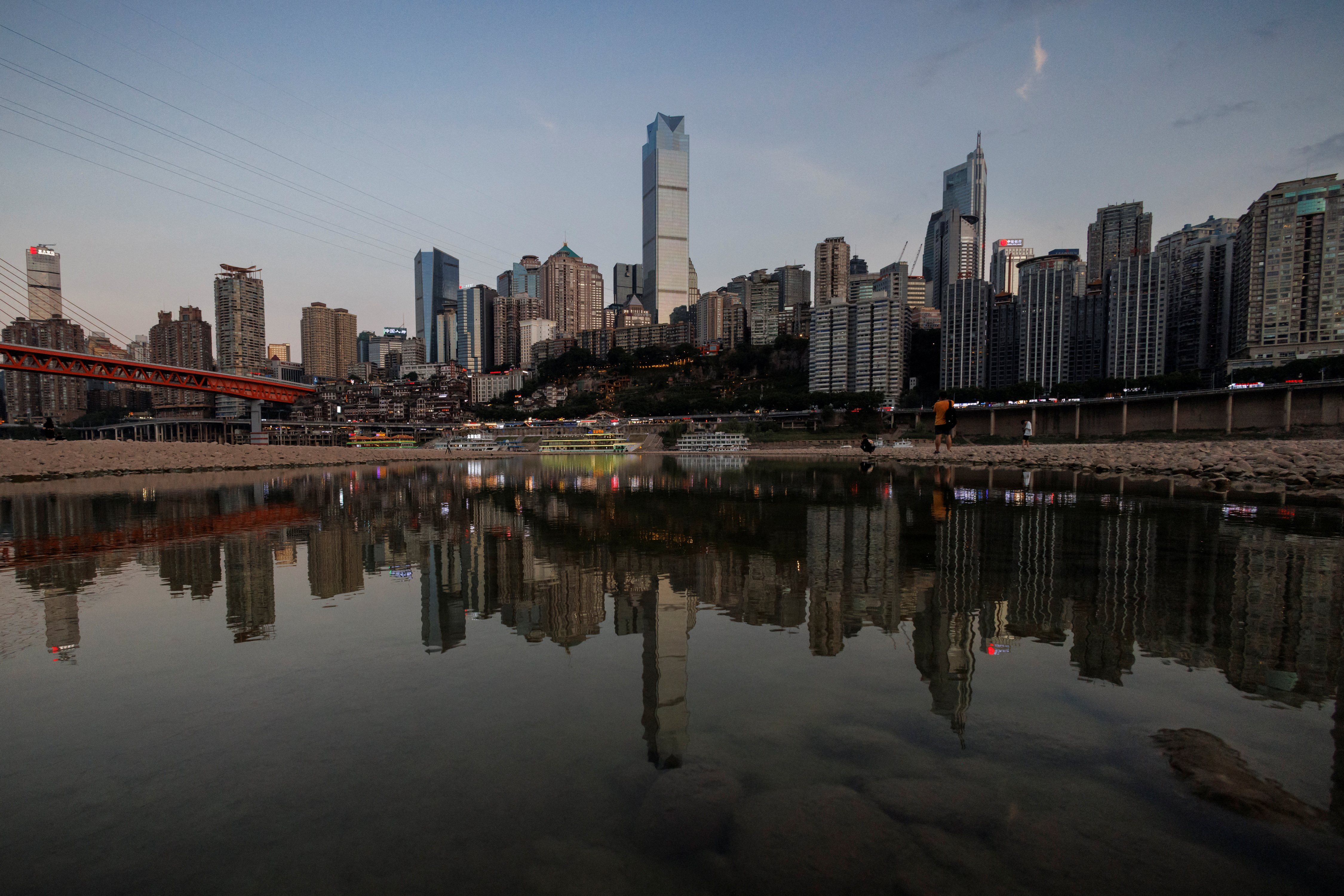 The city skyline is reflected in a pool left on the dry riverbed of the receding Jialing river, a tributary of the Yangtze, that is approaching record-low water levels during a regional drought in Chongqing