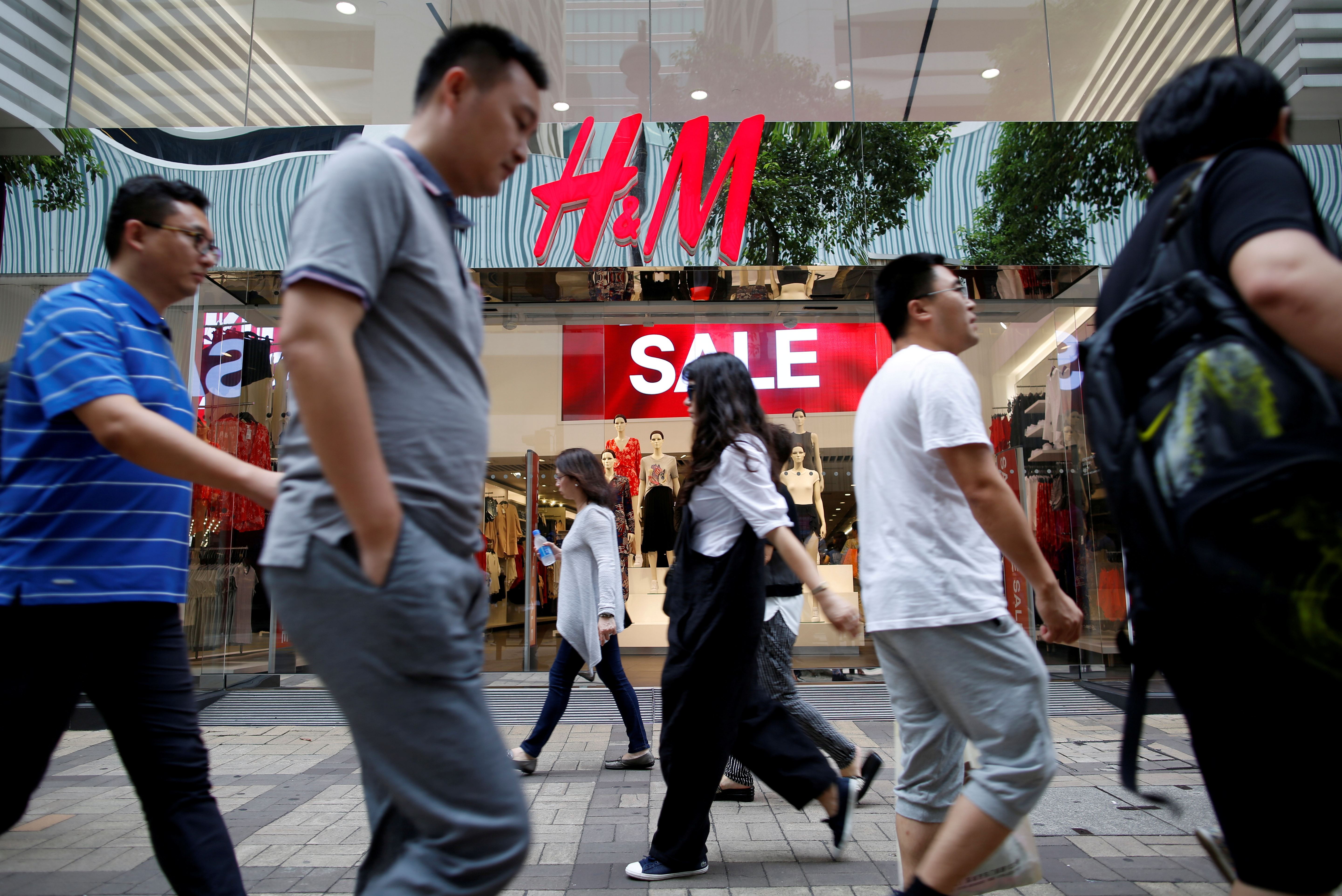 People walk past a H&M fashion chain store at Tsim Sha Tsui shopping district in Hong Kong