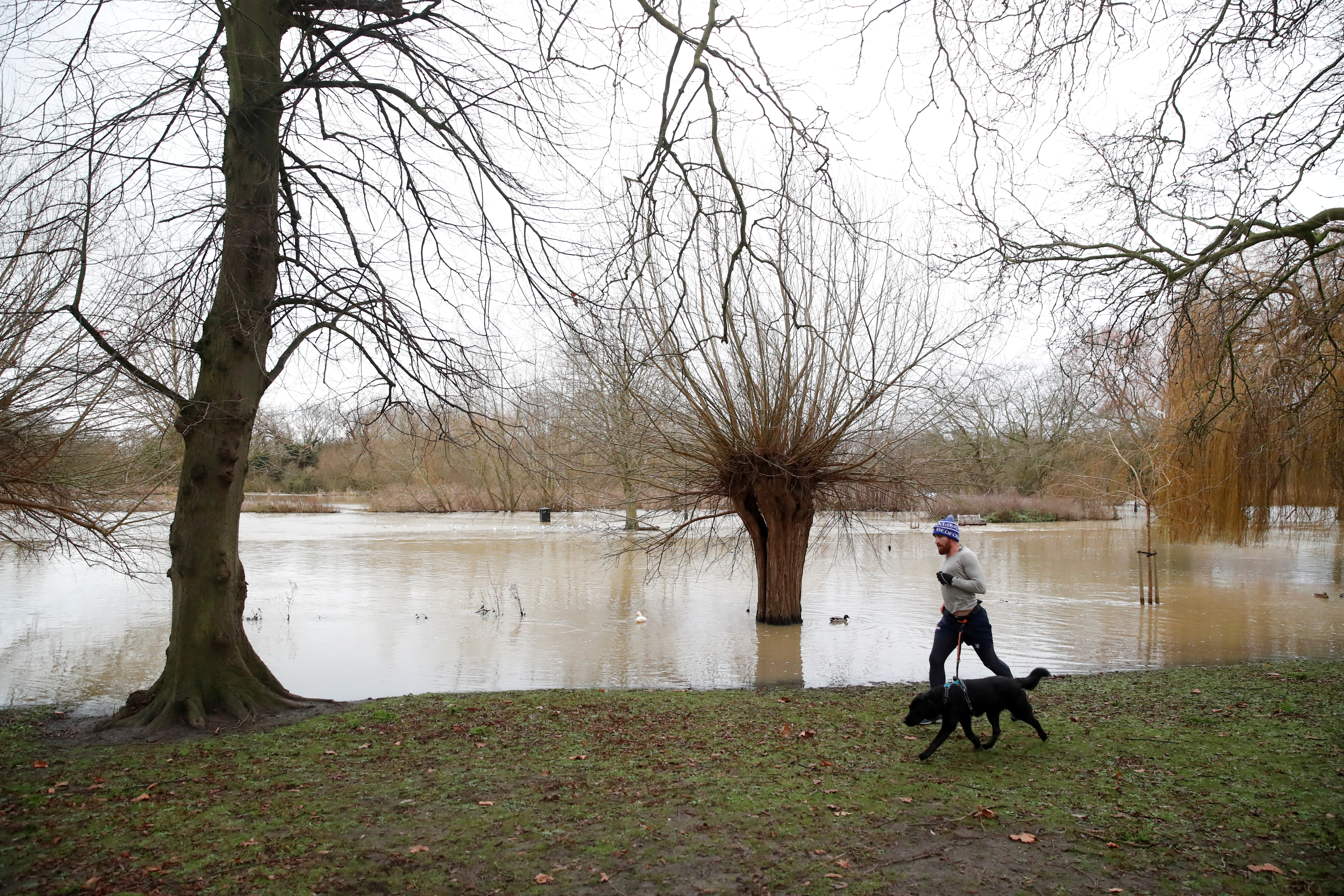 A man runs with his dog on the embankment of the River Great Ouse in Bedford, Britain, December 26, 2020. REUTERS/Andrew Boyers/File Photo