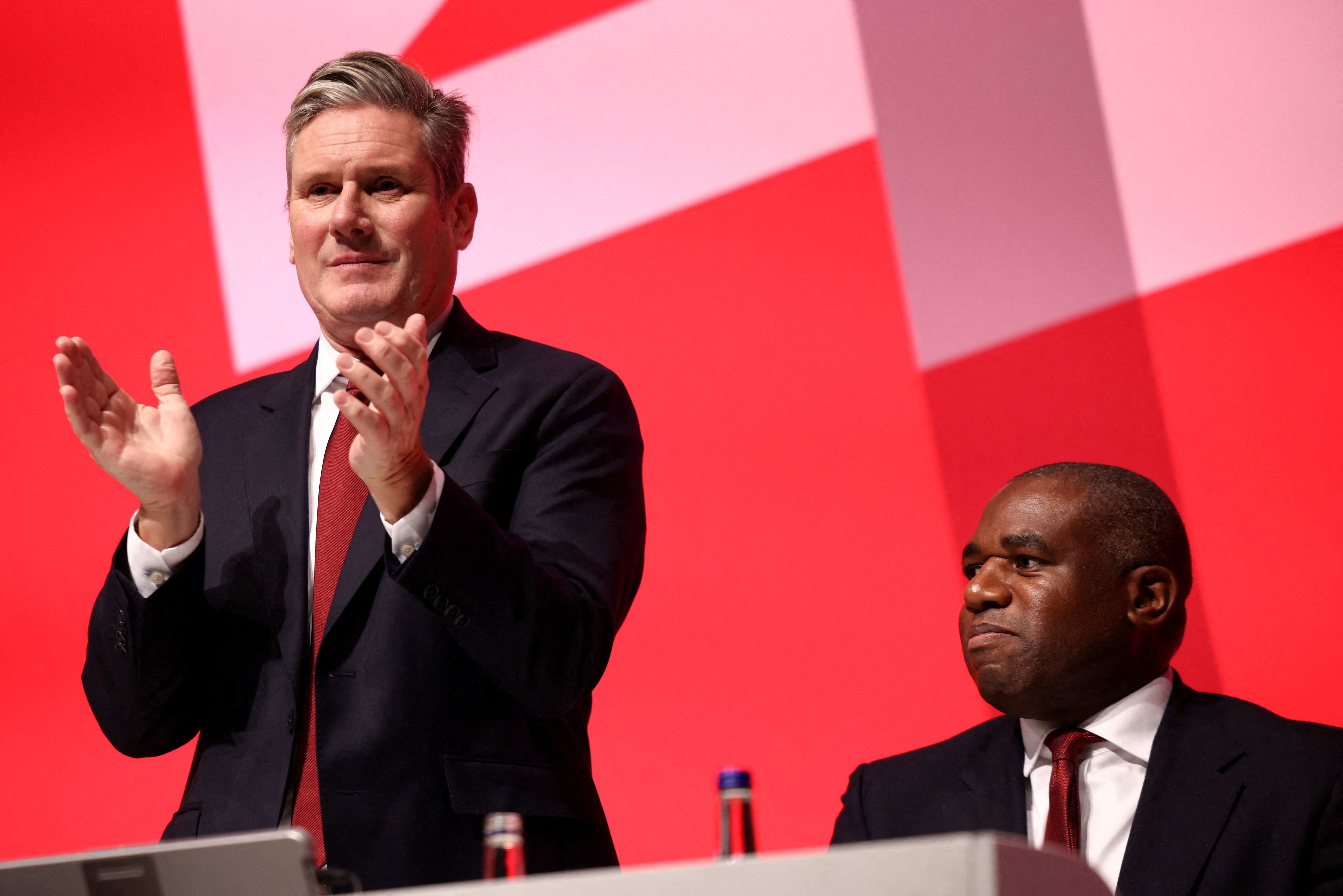 British Labour Party leader Keir Starmer applauds next to Shadow Foreign Secretary David Lammy during Britain's Labour Party annual conference