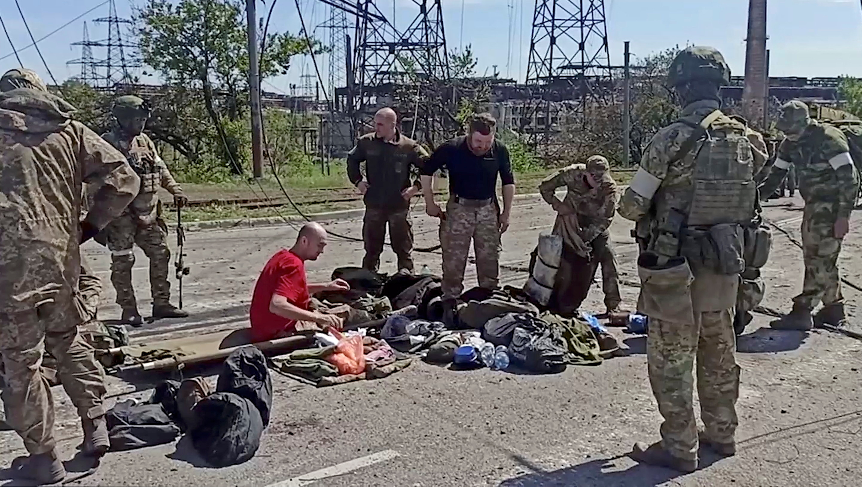 Service members of Ukrainian forces who have surrendered after weeks holed up at Azovstal steel works are being searched in Mariupol