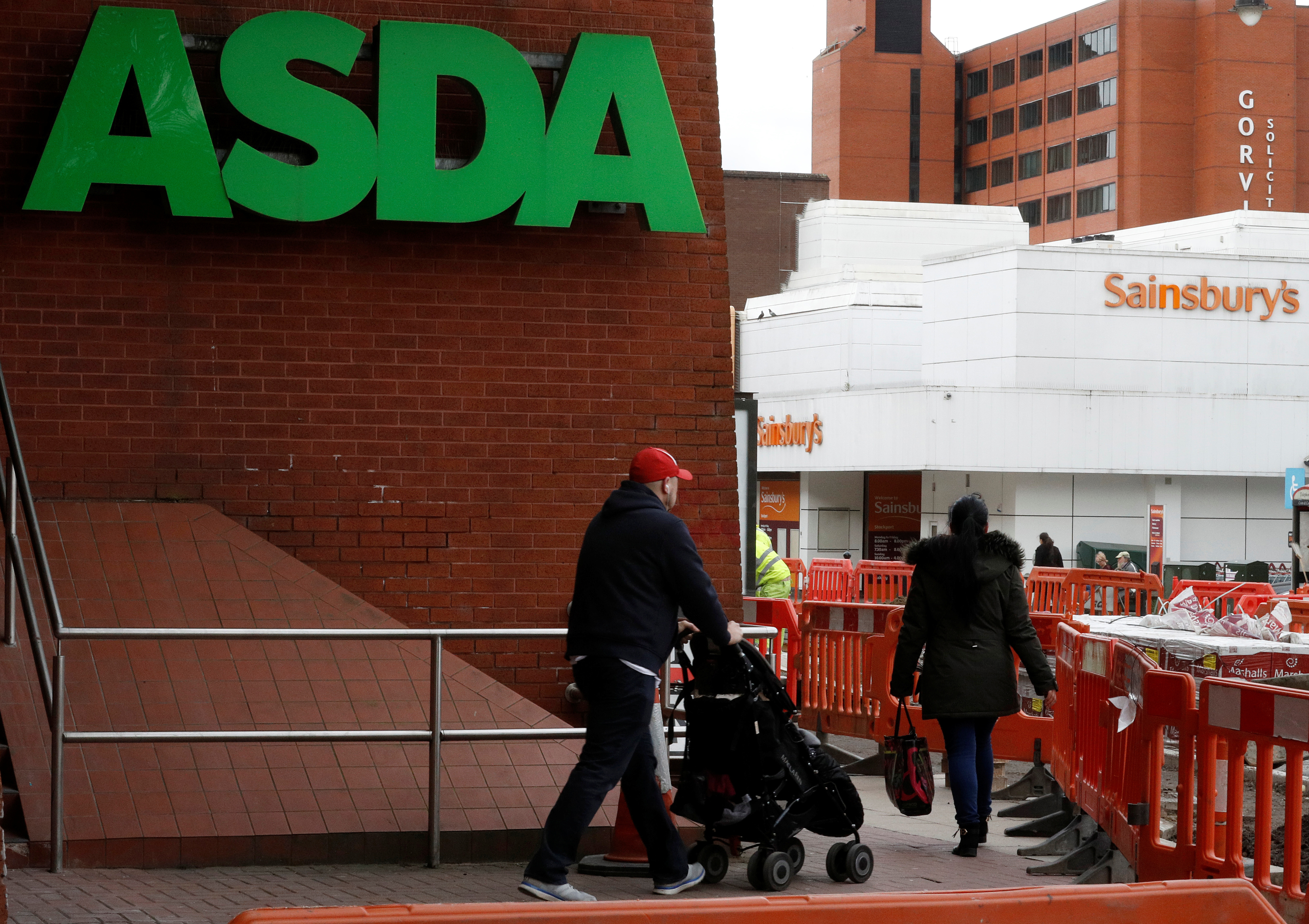 People walk past branches of ASDA and Sainsbury's in Stockport.