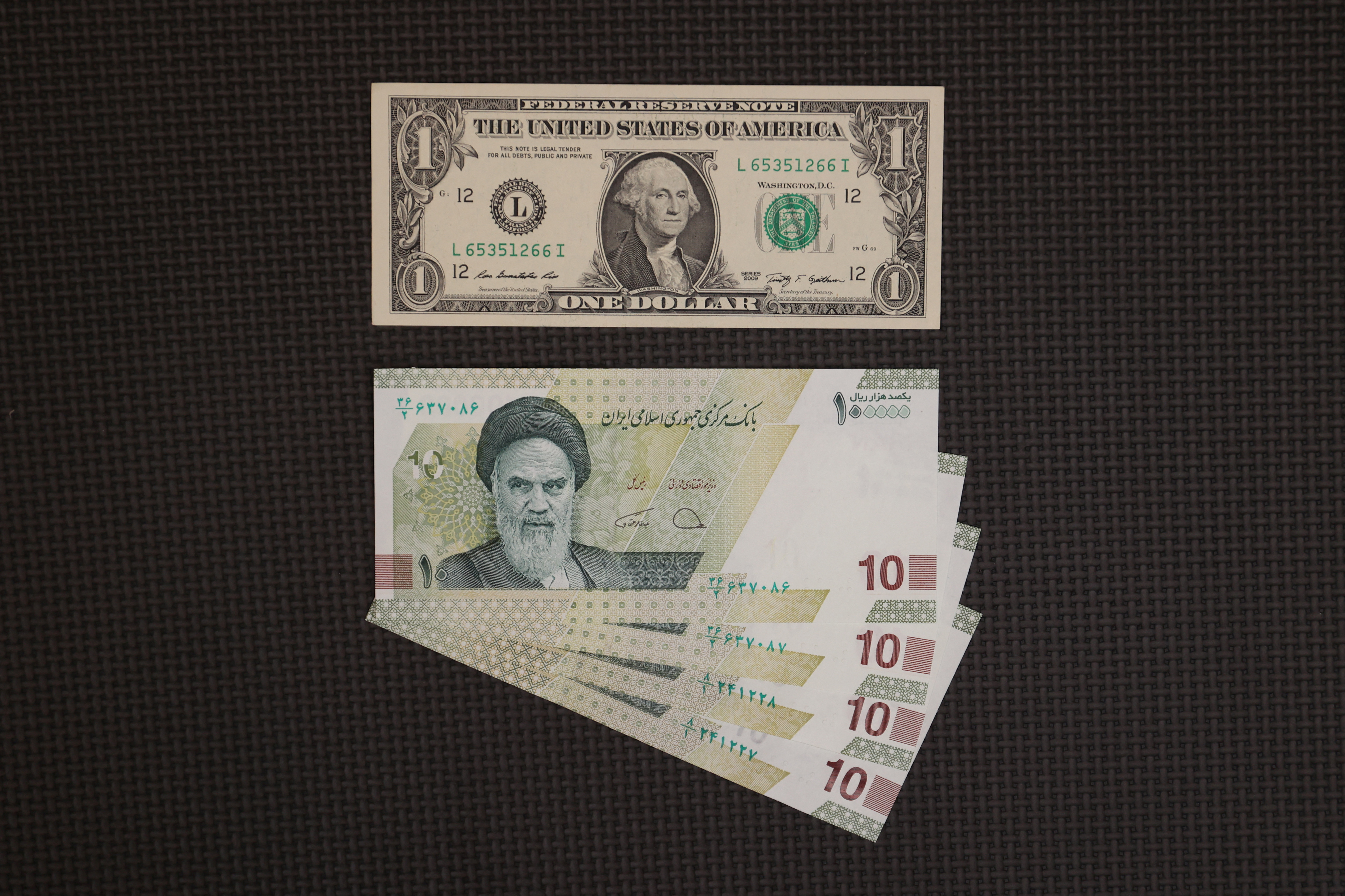 A U.S. one-dollar bill is seen against four 10000 Iranian rial bills in an exchange shop in Tehran