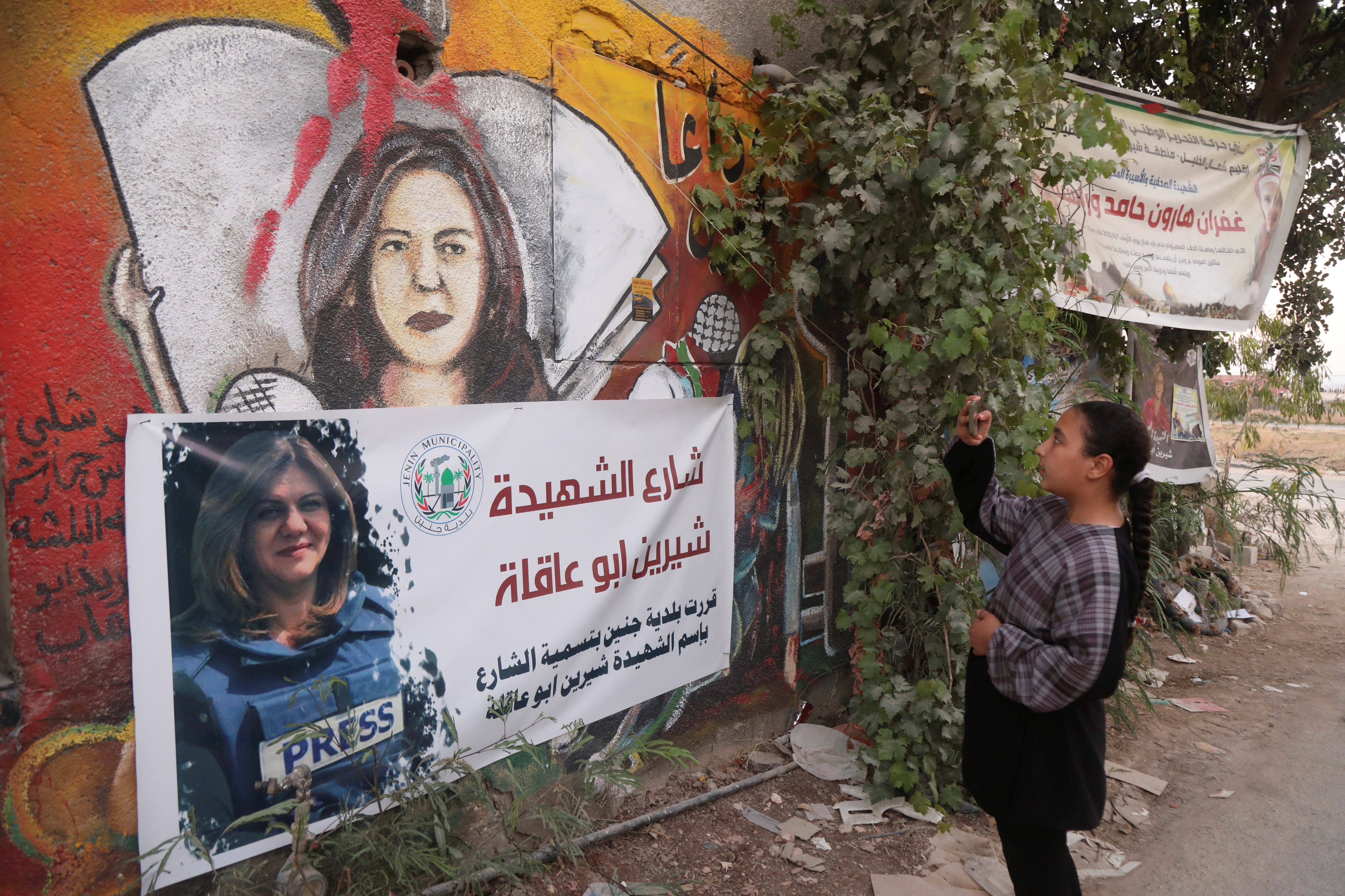 Palestinian girl takes pictures at the scene where Al Jazeera reporter Shireen Abu Akleh was shot dead during an Israeli raid, in Jenin