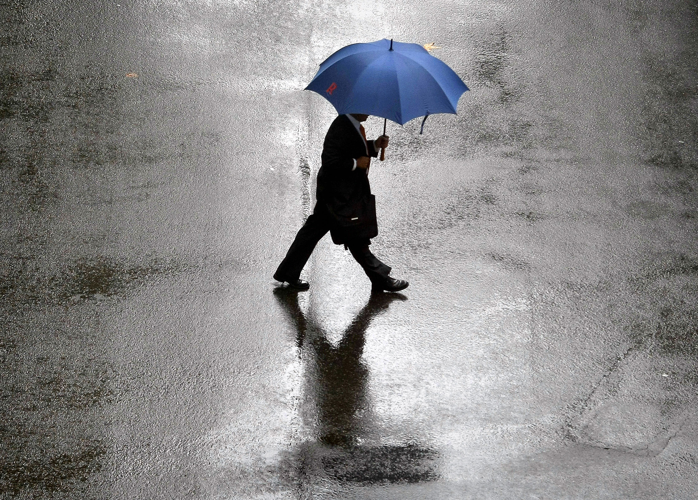 Man wearing business suit crosses central Sydney street in rain
