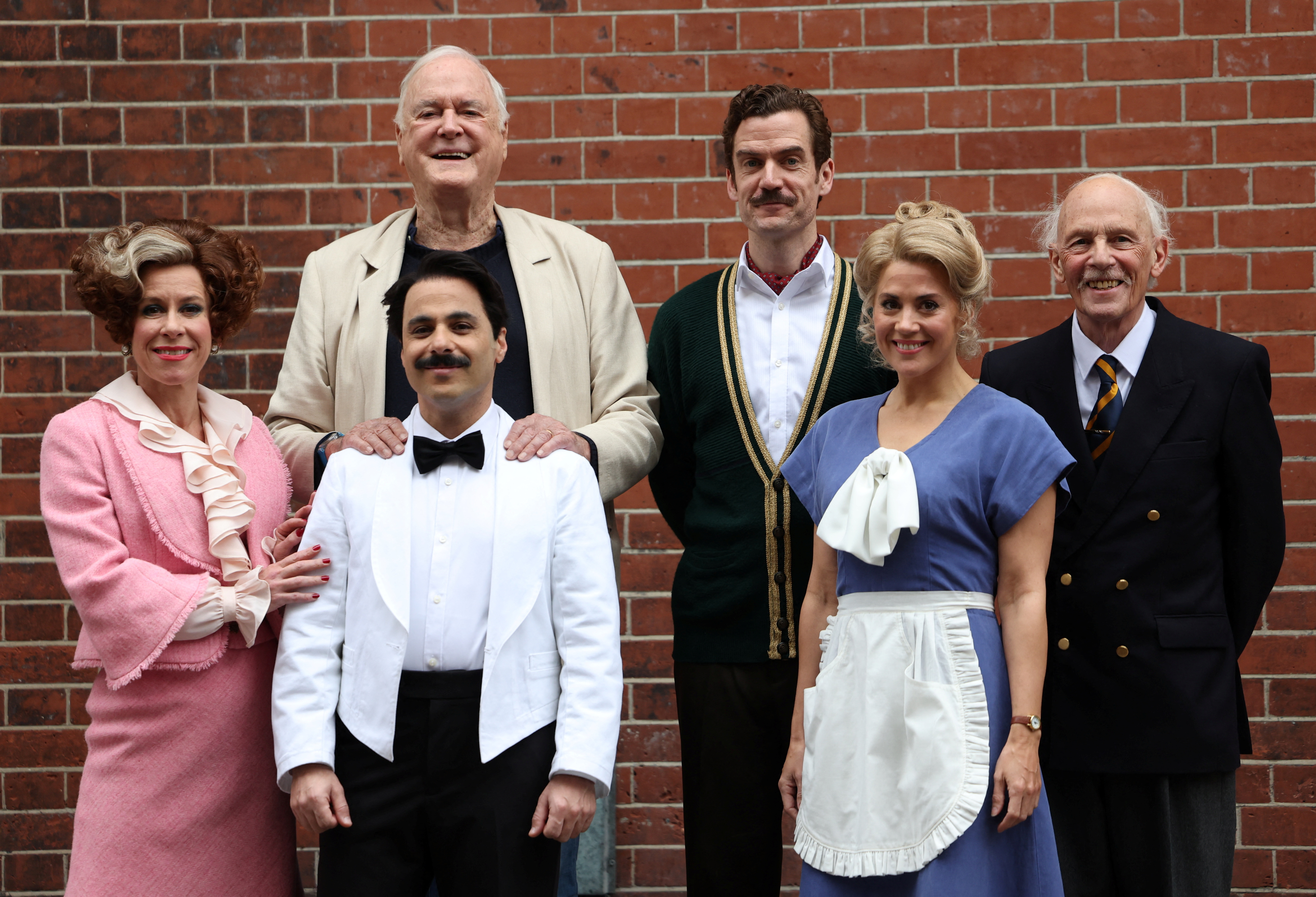 British actor John Cleese poses with cast members from the play Fawlty Towers in London