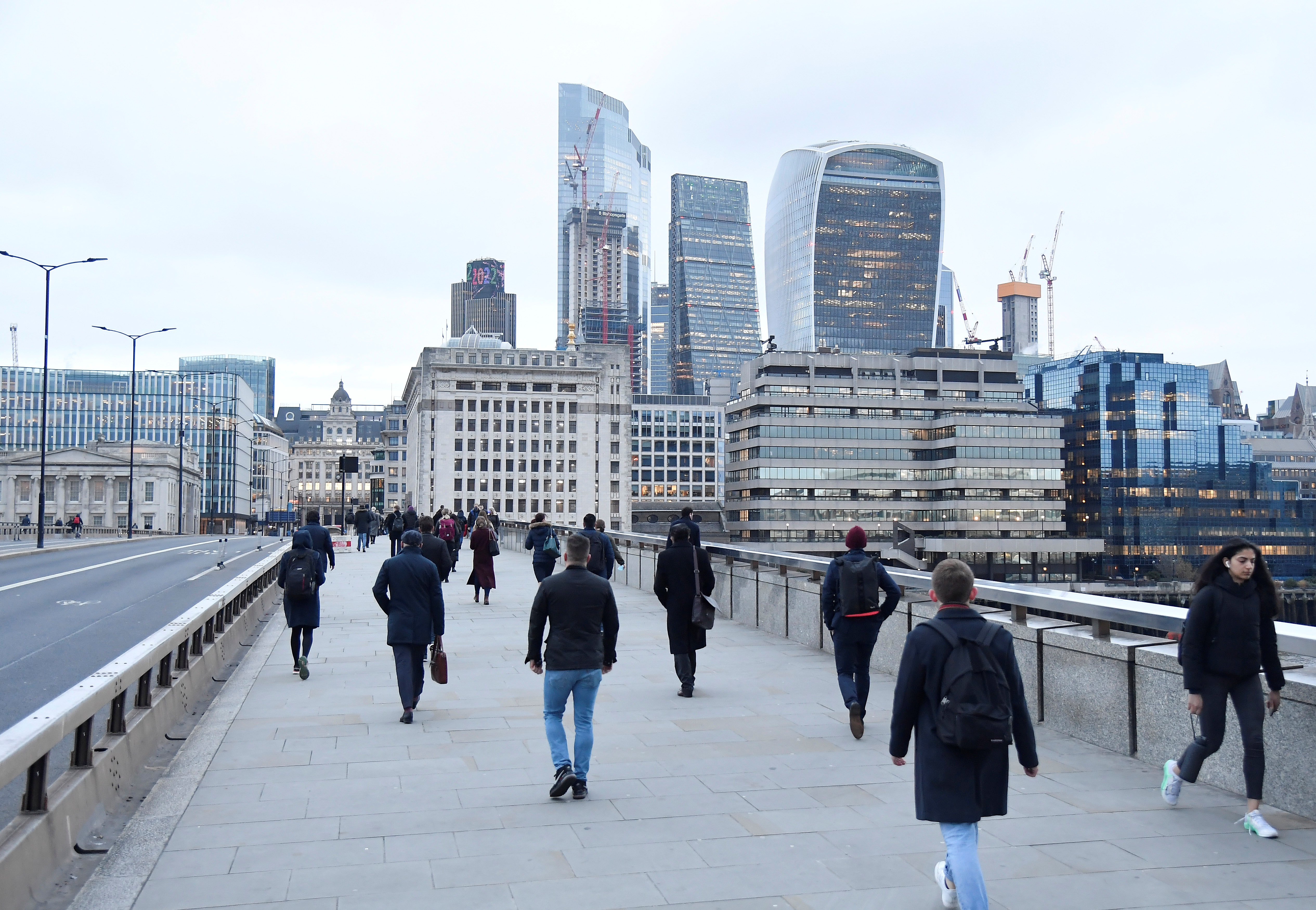 Workers cross London Bridge during the morning rush-hour, in London