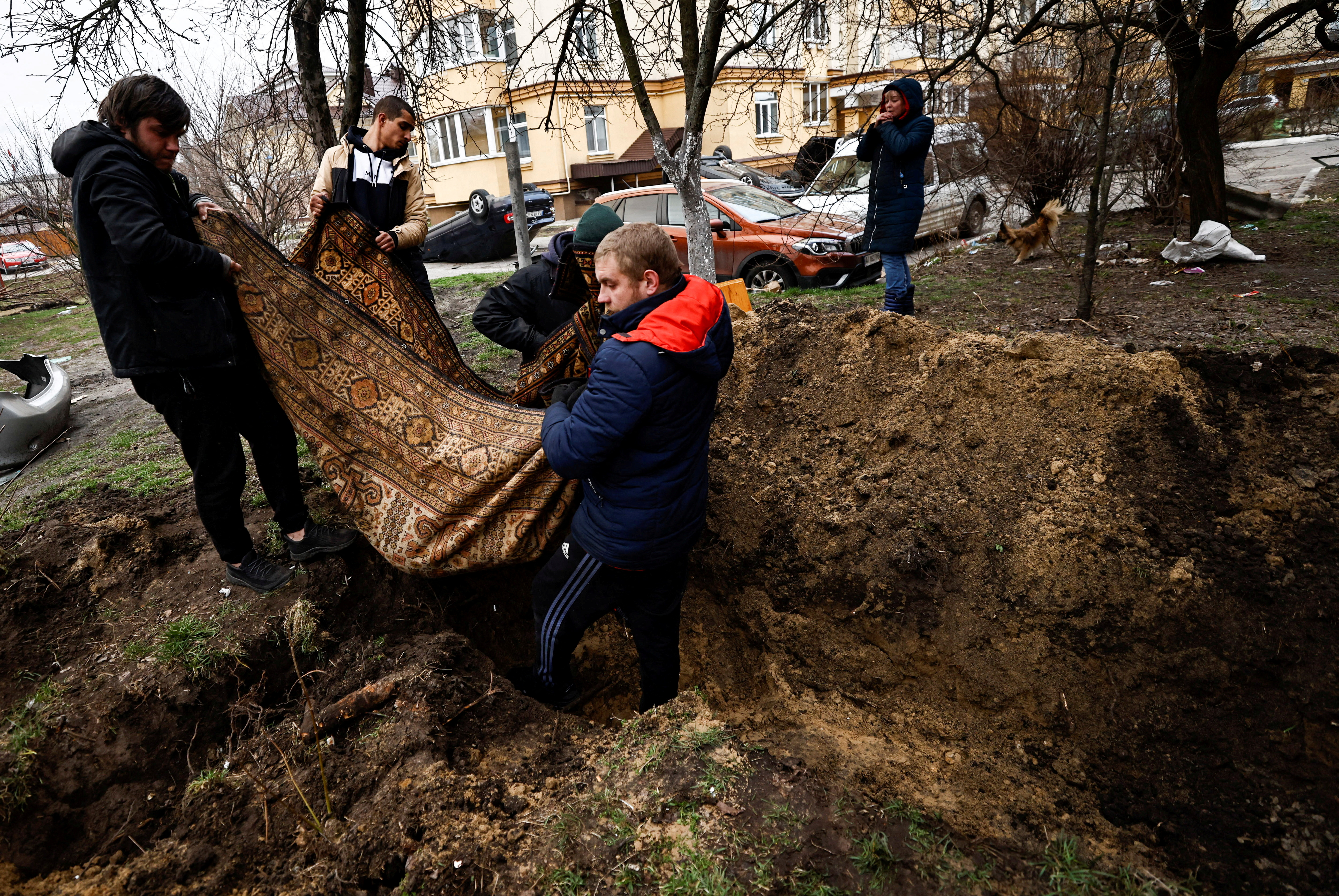 Serhii Lahovskyi and other residents carry the body of Ihor Lytvynenko, who according to residents was killed by Russian Soldiers to bury him, in Bucha
