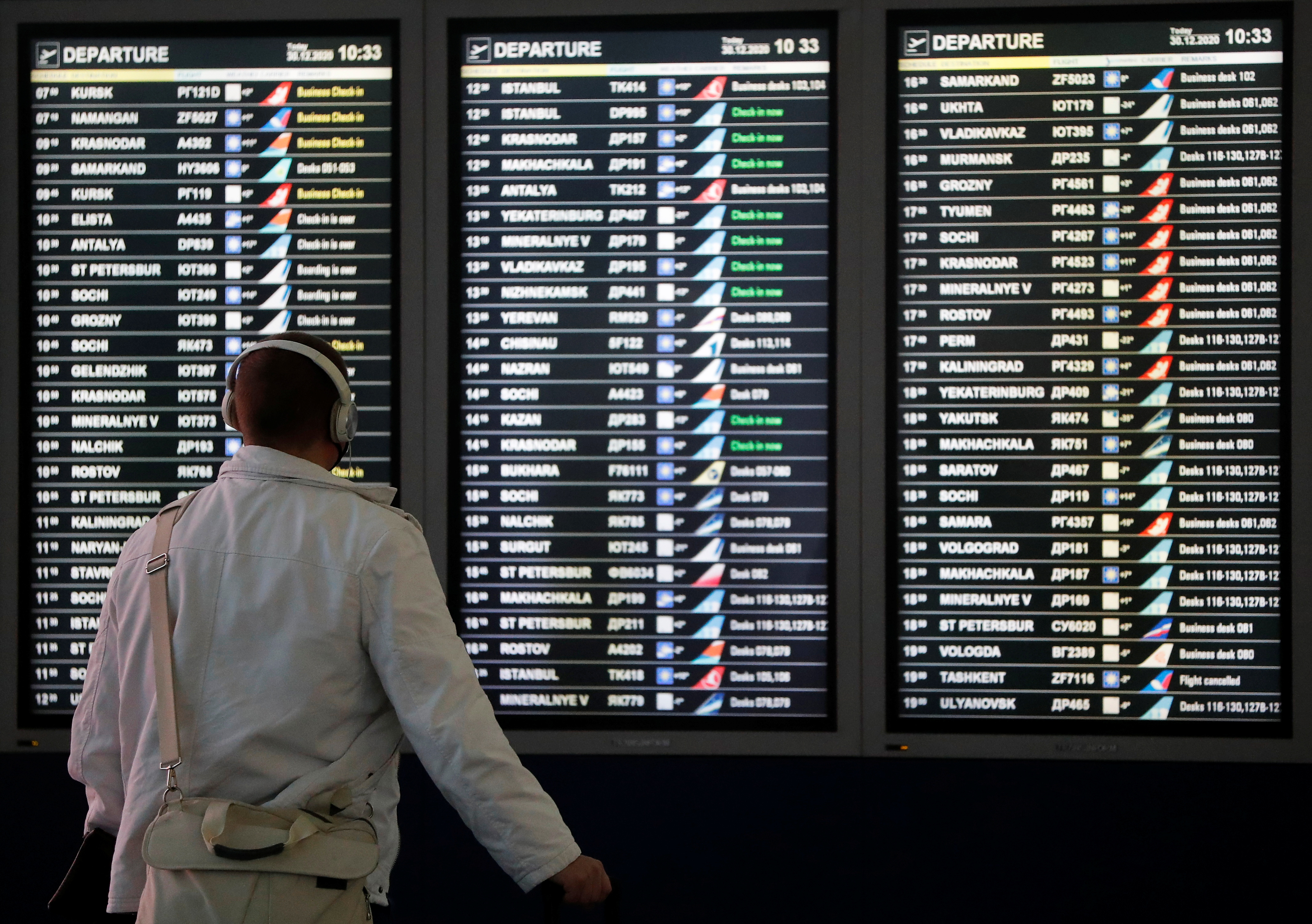 A man looks at a flight information board at the departure zone of Vnukovo International Airport in Moscow