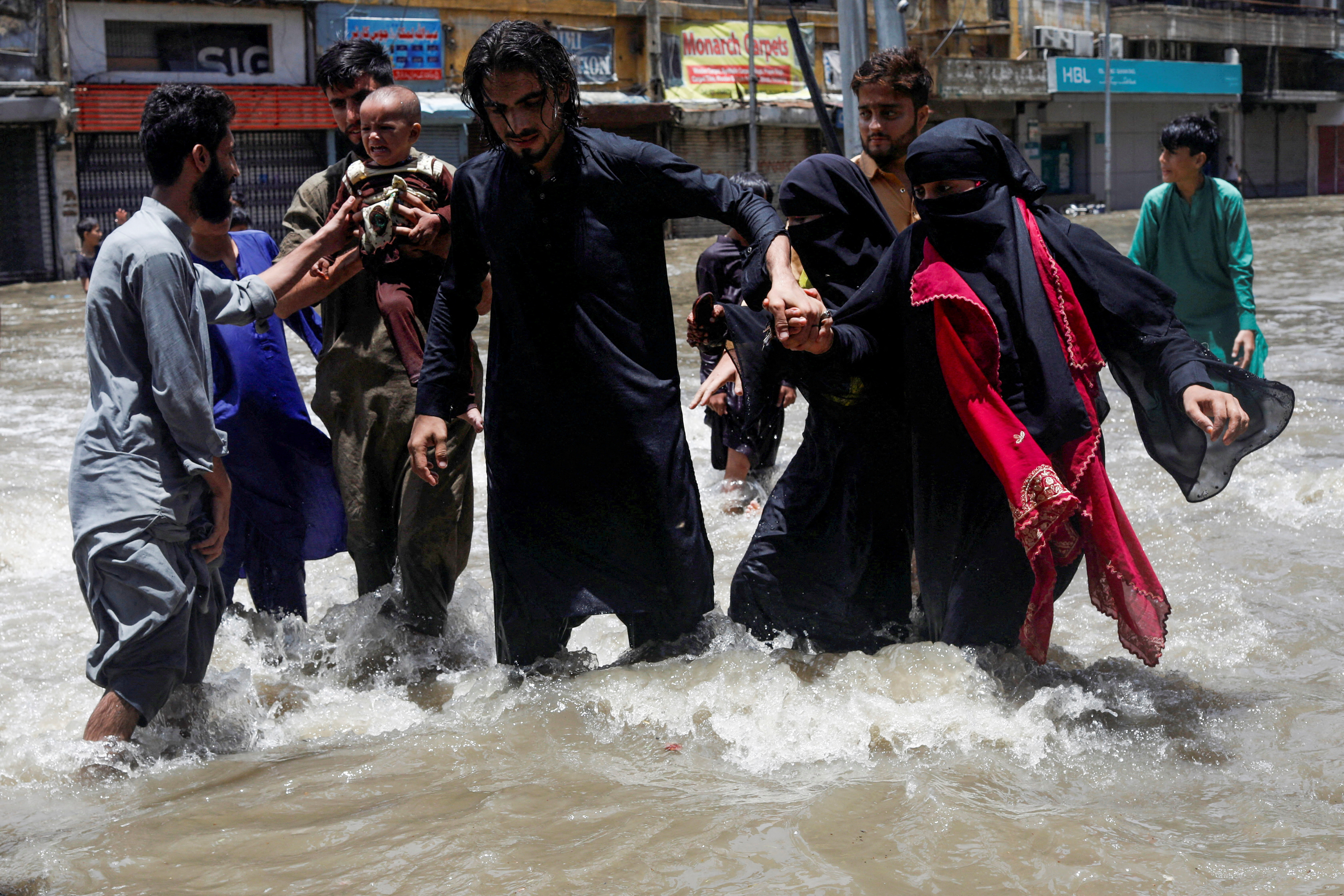 A family wades through a flooded street during the monsoon season, in Karachi