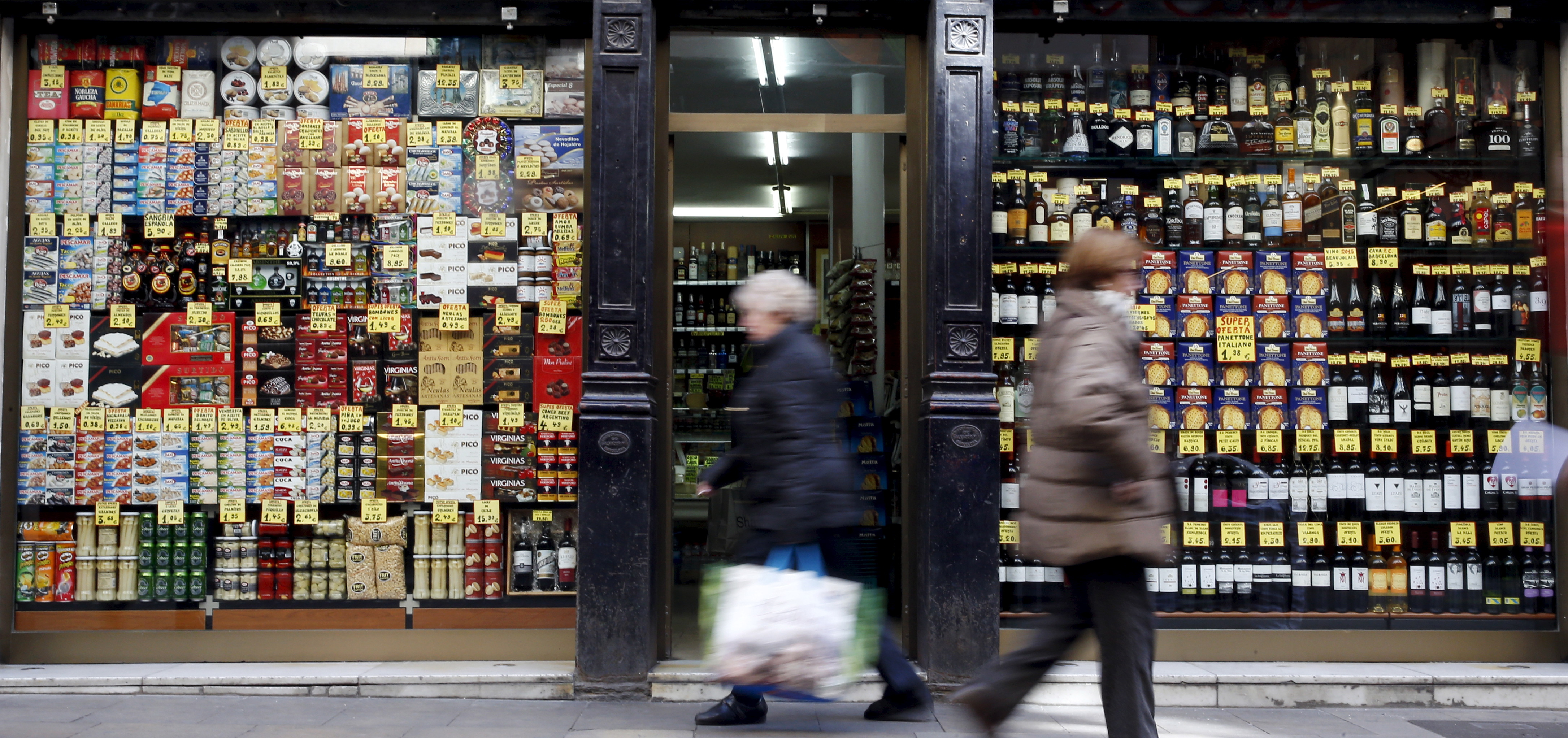 People walk past a grocery shop in central Barcelona, Spain