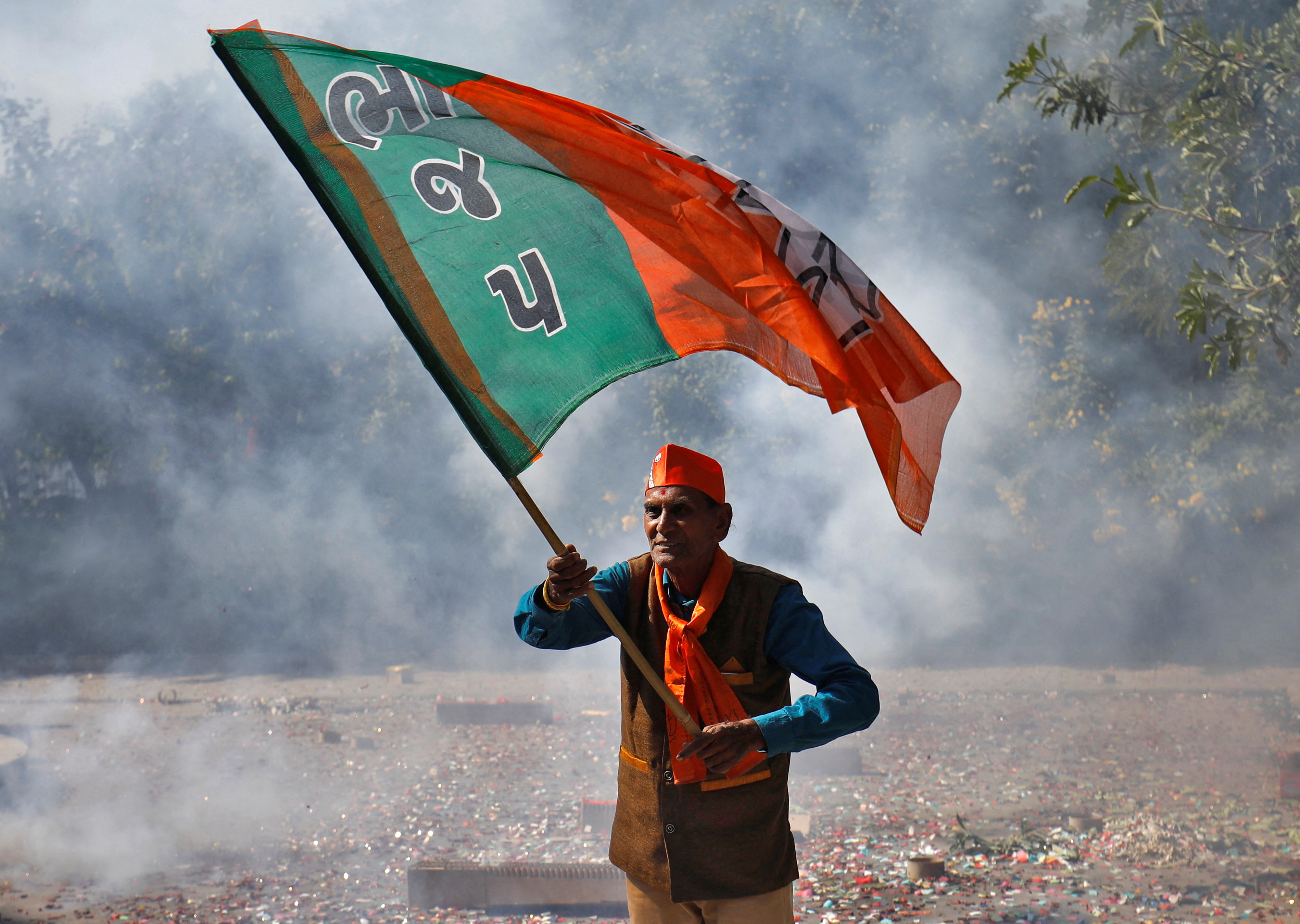 Supporter of BJP waves his party's flag during celebrations after learning of the initial poll results, in Gandhinagar