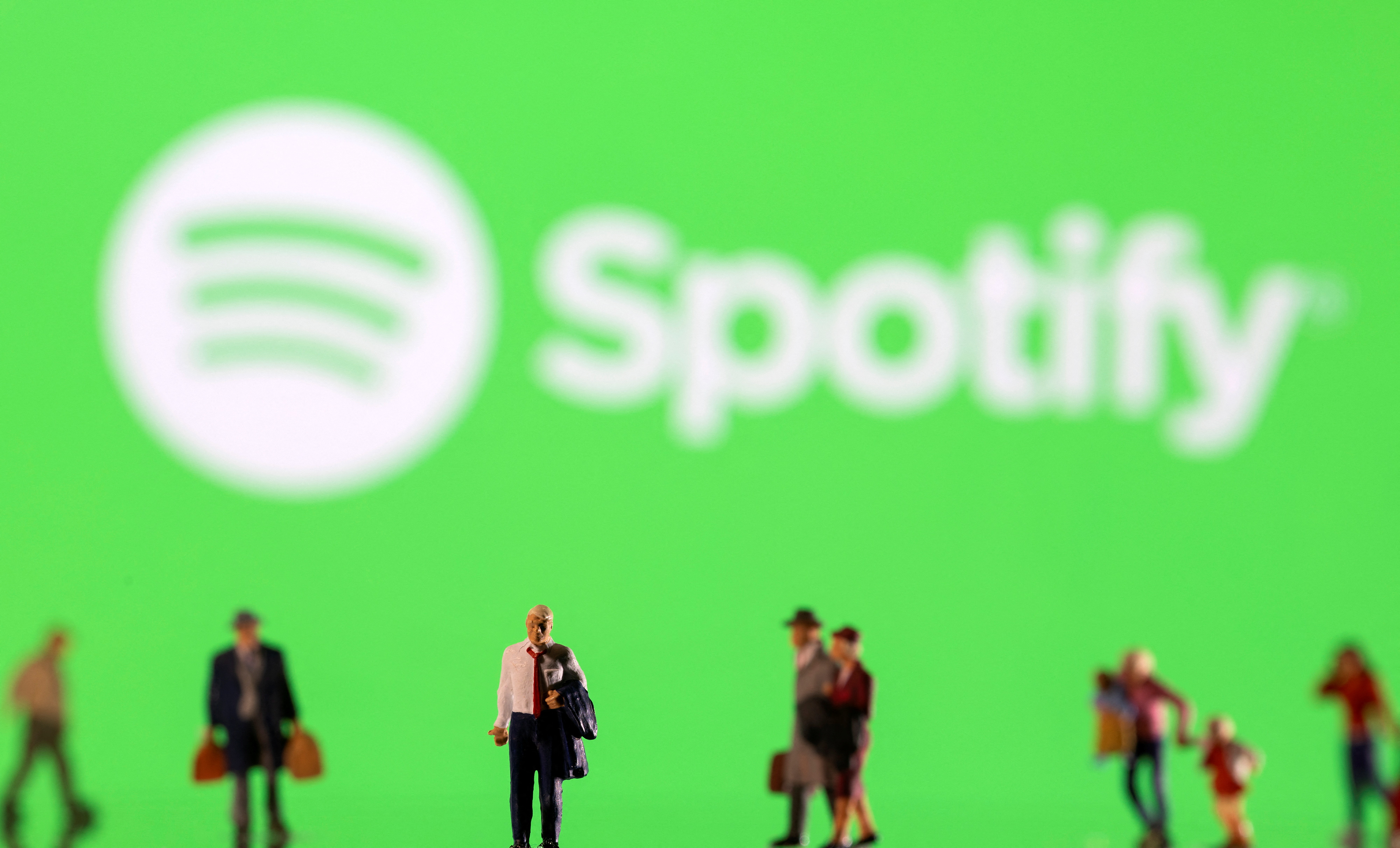 Resimde küçük figürler ve görüntülenen Spotify logosu gösterilmektedir