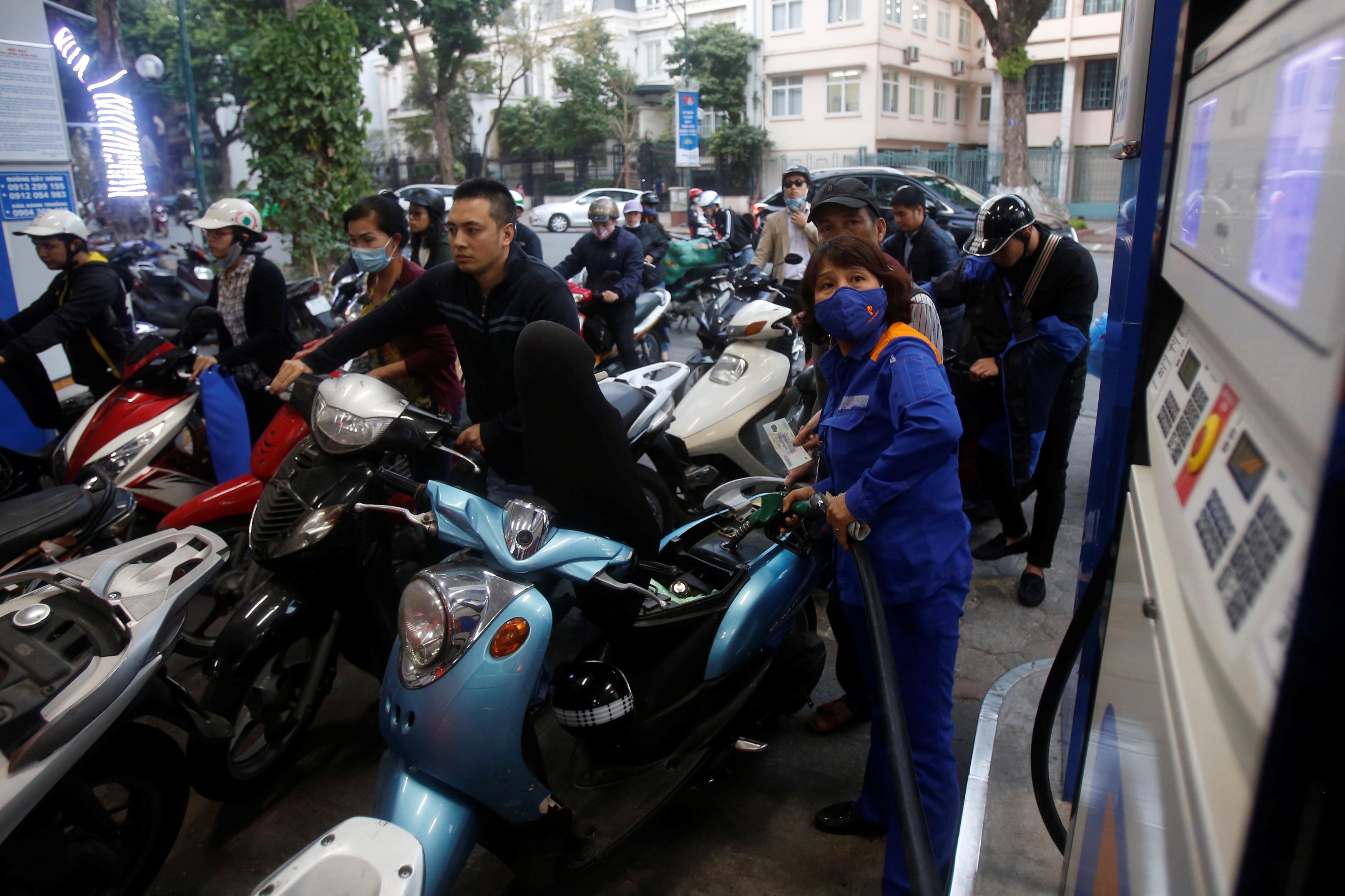 An employee pumps petrol for clients at a petrol station in Hanoi