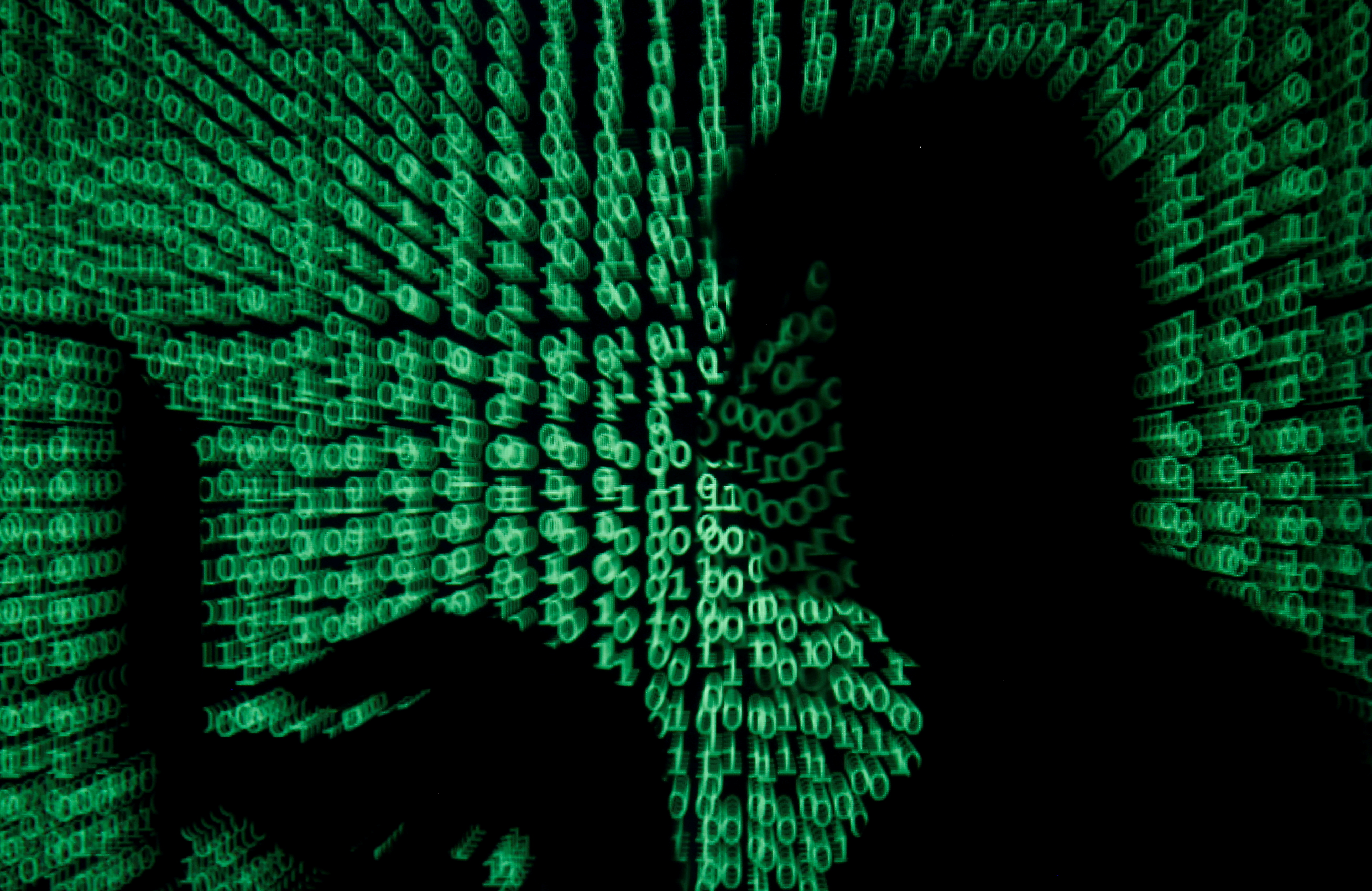 A man holds laptop computer as cyber code is projected on him in this illustration picture