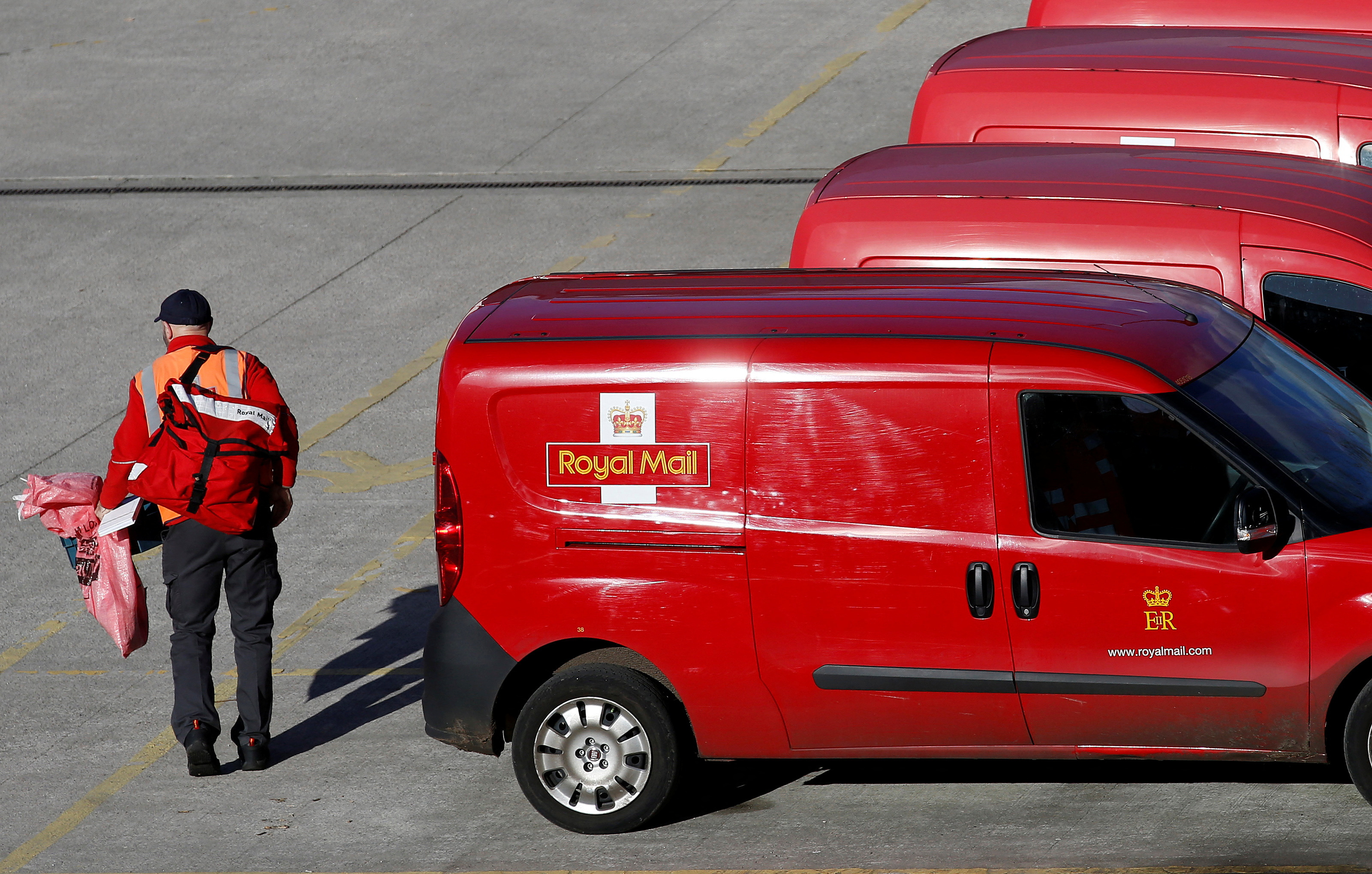 A postal worker carries mail bags from a van at a Royal Mail sorting office in Altrincham northern England