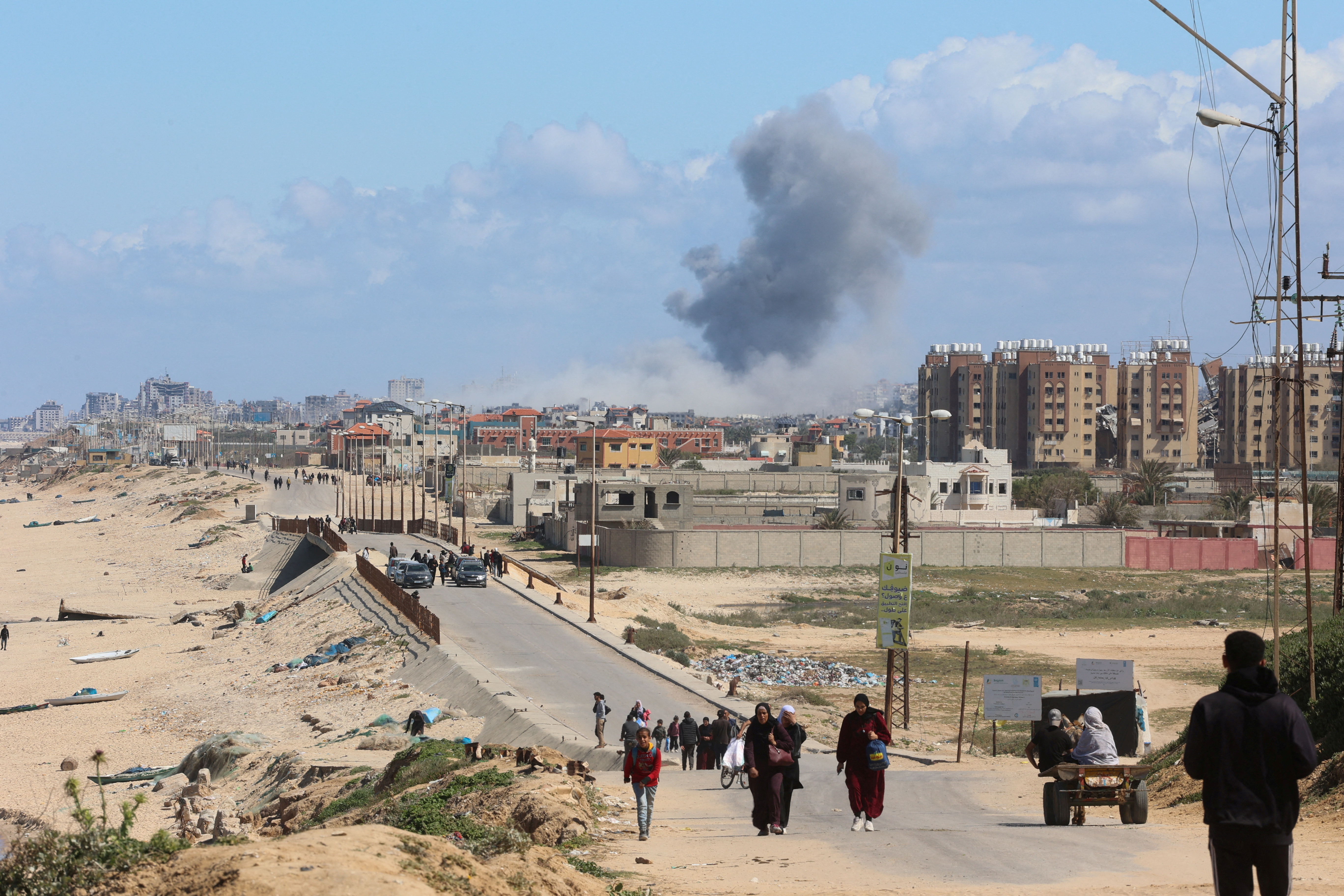Smoke rises following an Israeli strike as Palestinians fleeing north Gaza due to Israel’s military offensive move southward, at the central Gaza Strip