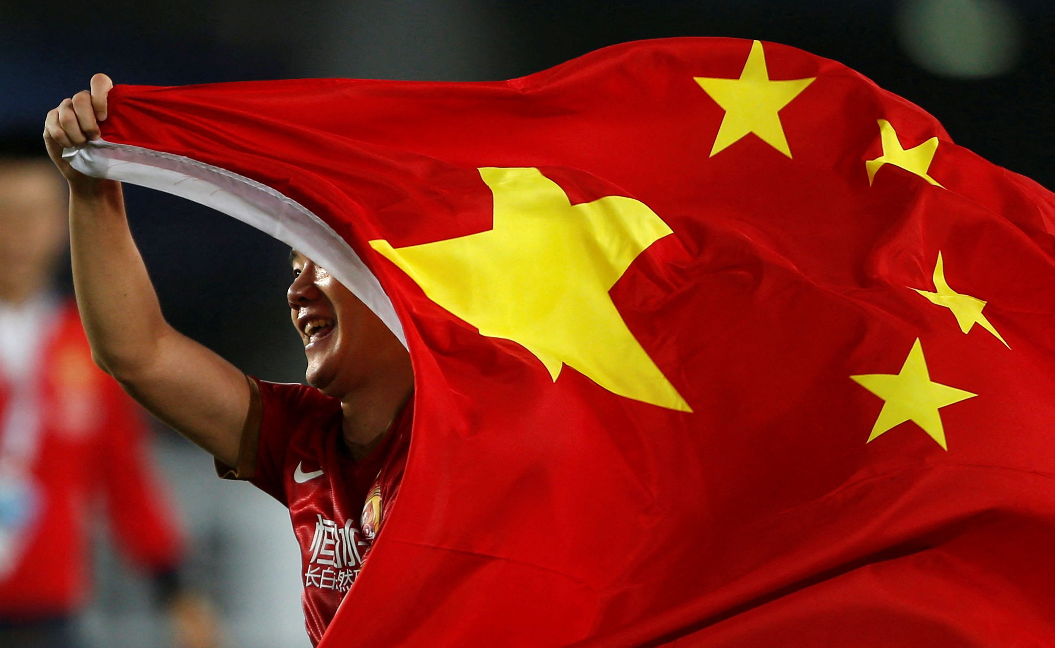Huang Bowen of China's Guangzhou Evergrande celebrates with the national flag after winning the team's final match of the AFC Champions' League against South Korea's FC Seoul in Guangzhou