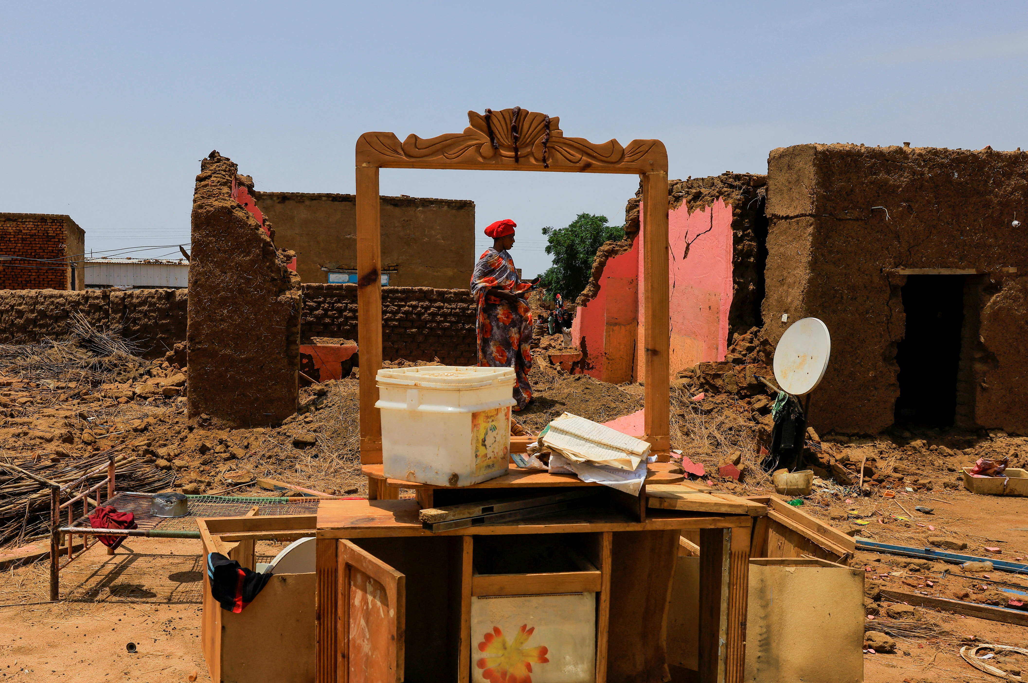 A woman collects her belongings after sustaining water damage to her house during floods in Jazeera State