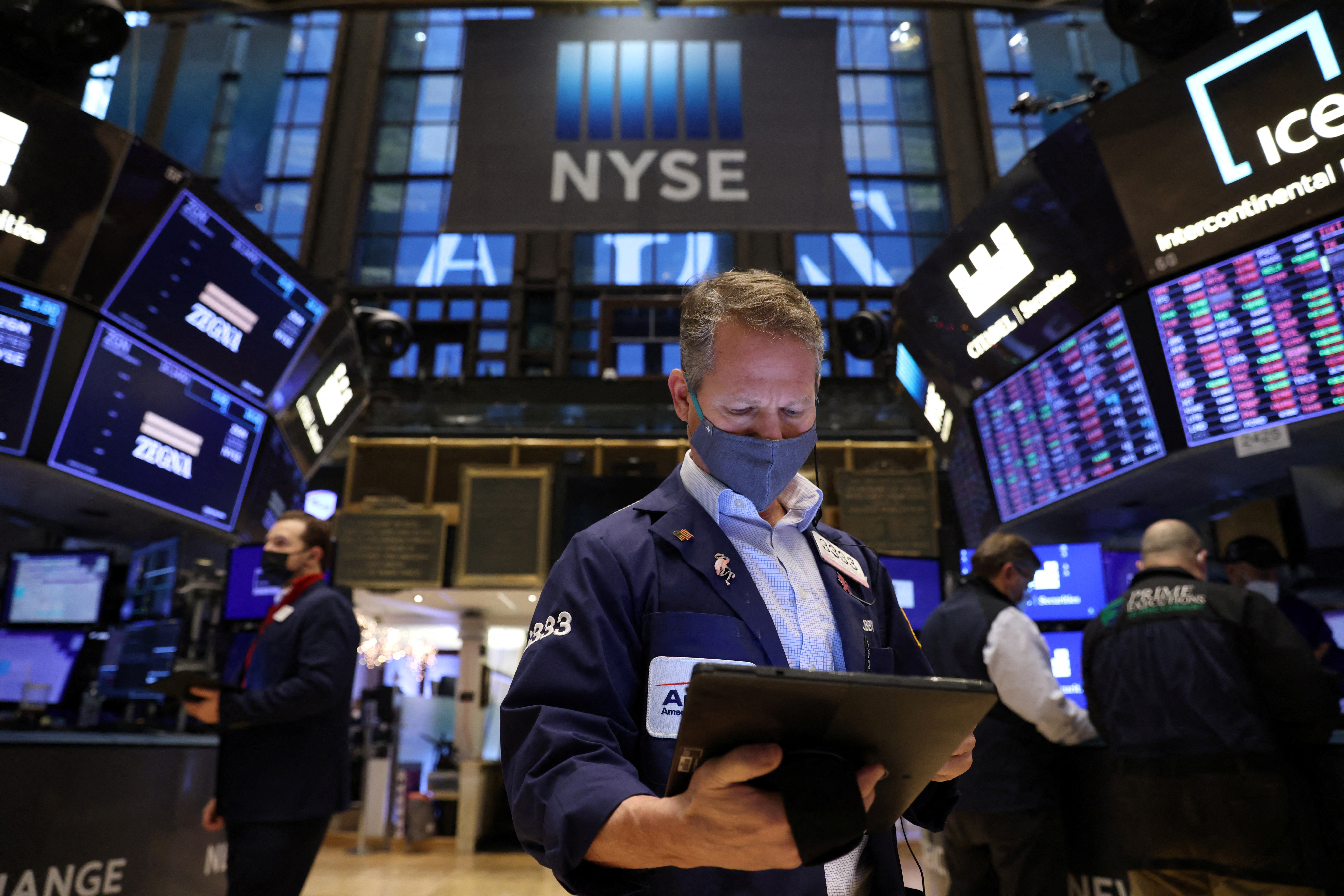 A trader in a face mask works on the trading floor at the New York Stock Exchange (NYSE) as the Omicron coronavirus variant continues to spread in Manhattan, New York City, U.S., December 20, 2021. REUTERS/Andrew Kelly