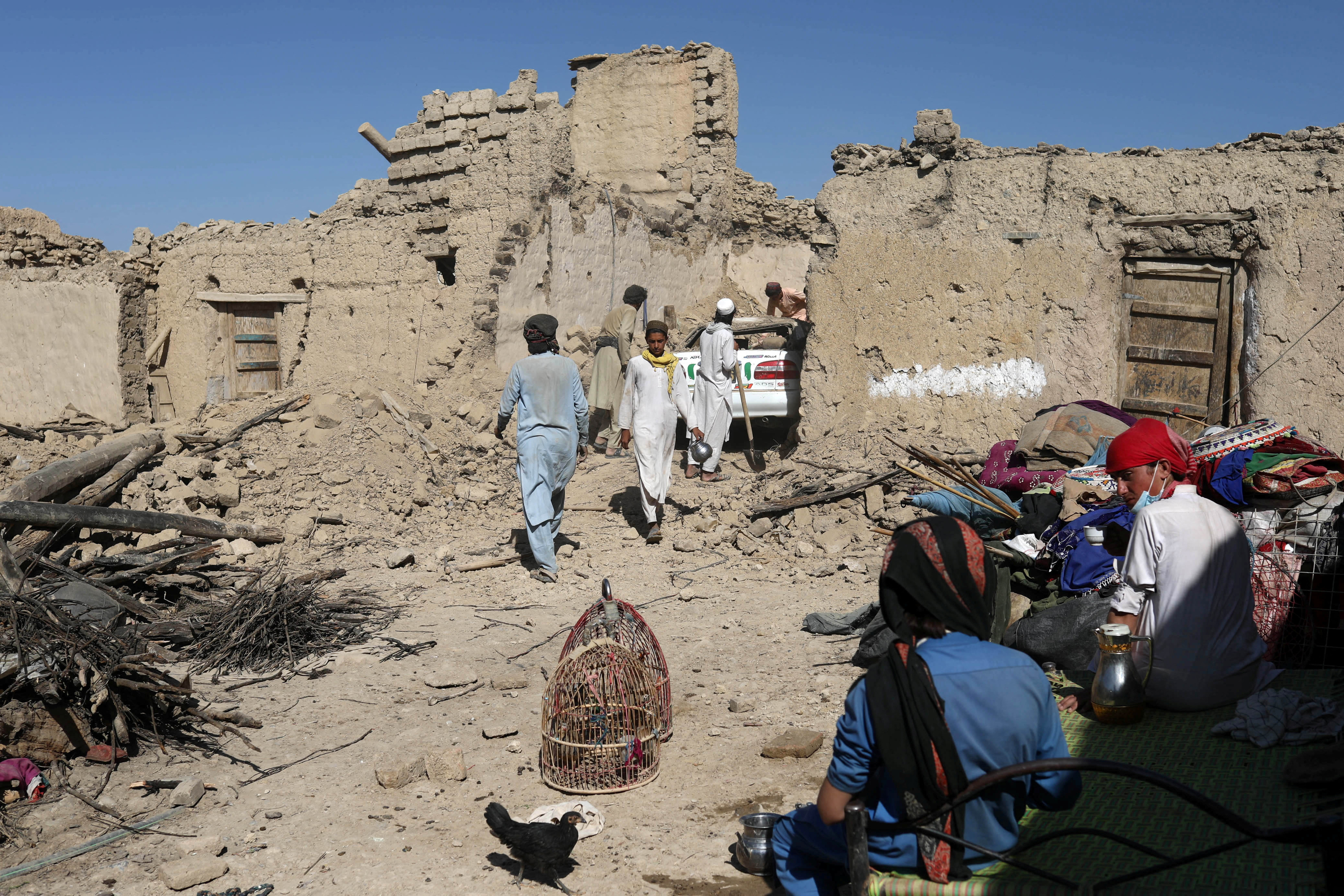 Afghan men try to retrieve a car from the debris of damaged houses after the recent earthquake in Wor Kali village