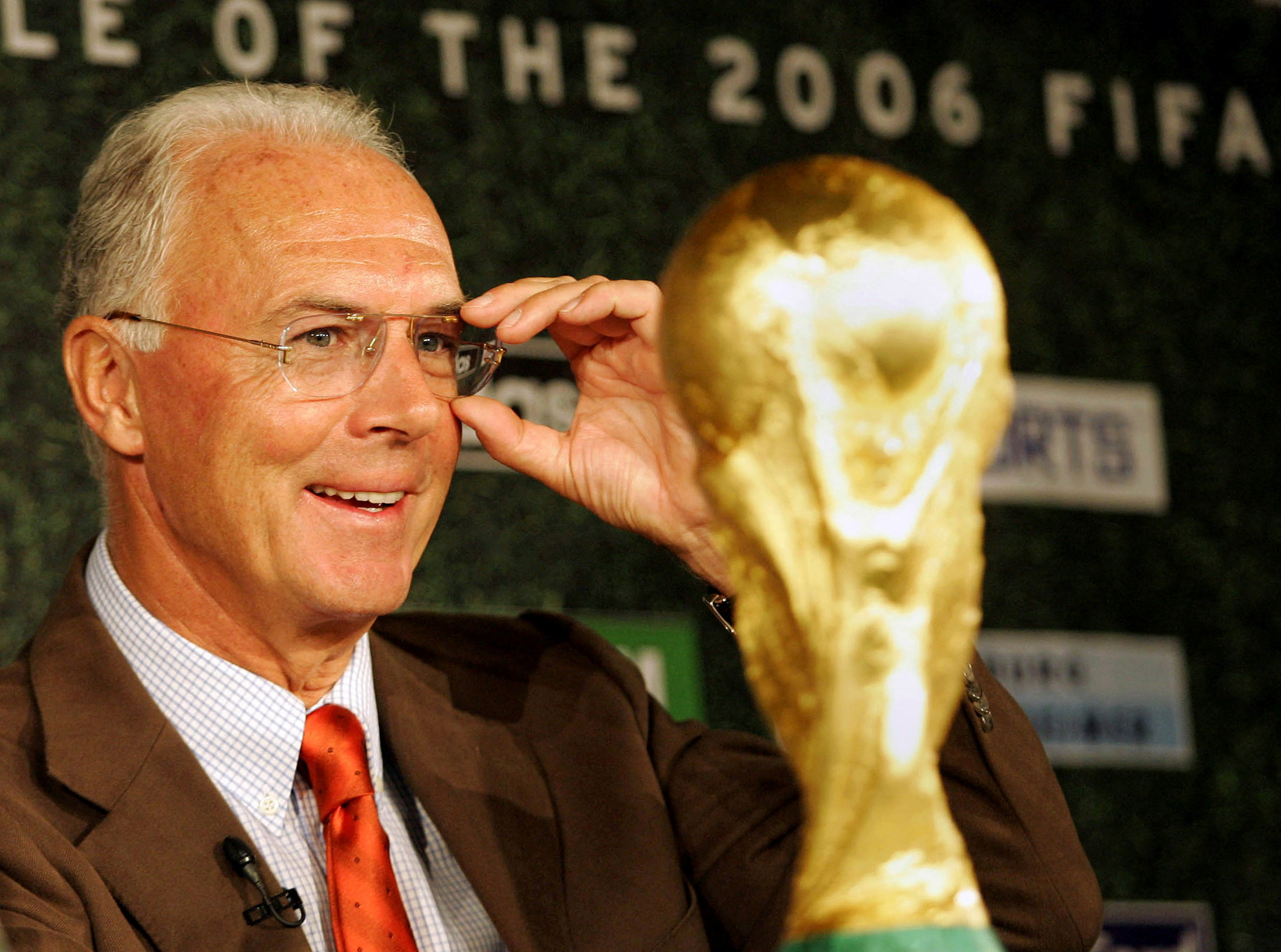 Franz Beckenbauer looks at the soccer world cup trophy during a news conference in Berlin.