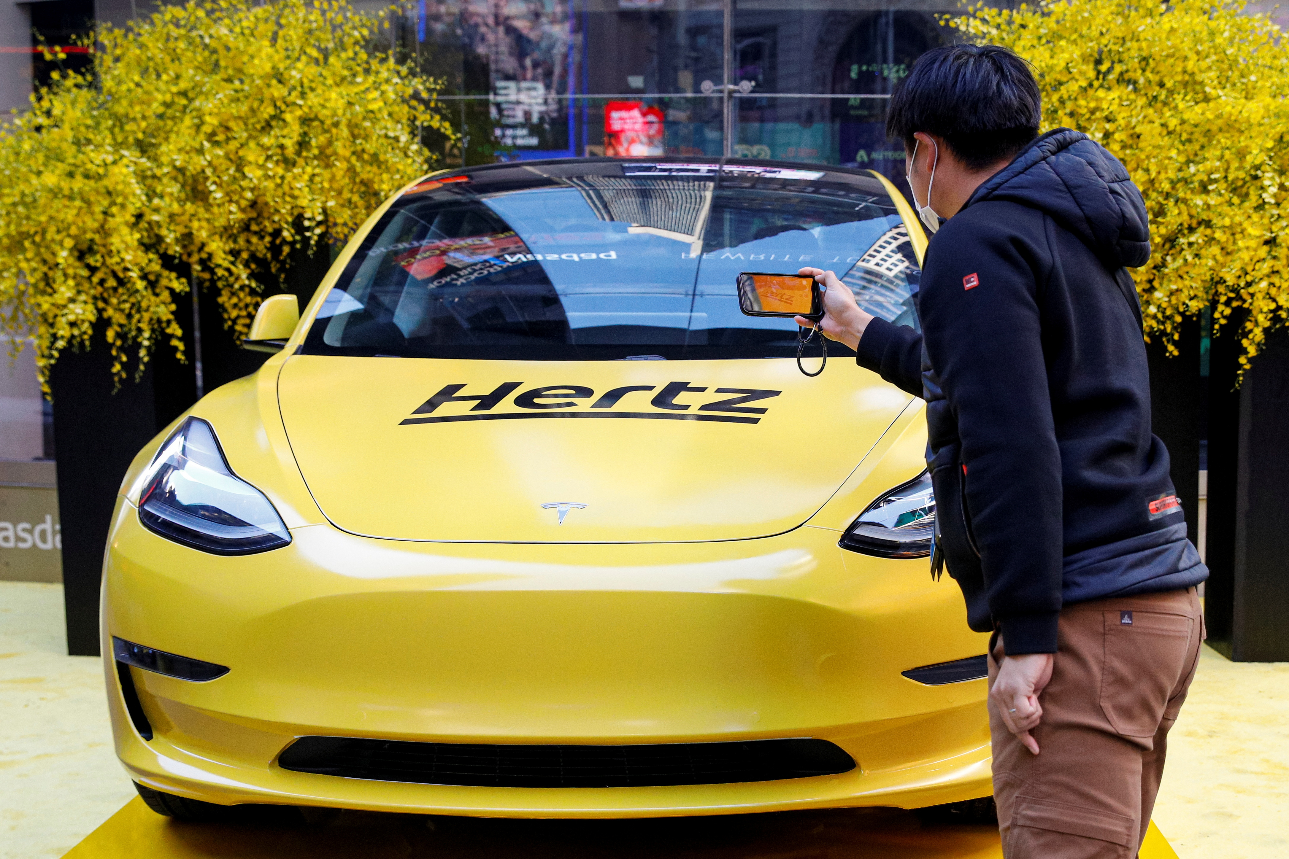 A man photographs a Hertz Tesla electric vehicle displayed during the Hertz Corporation IPO at the Nasdaq in New York