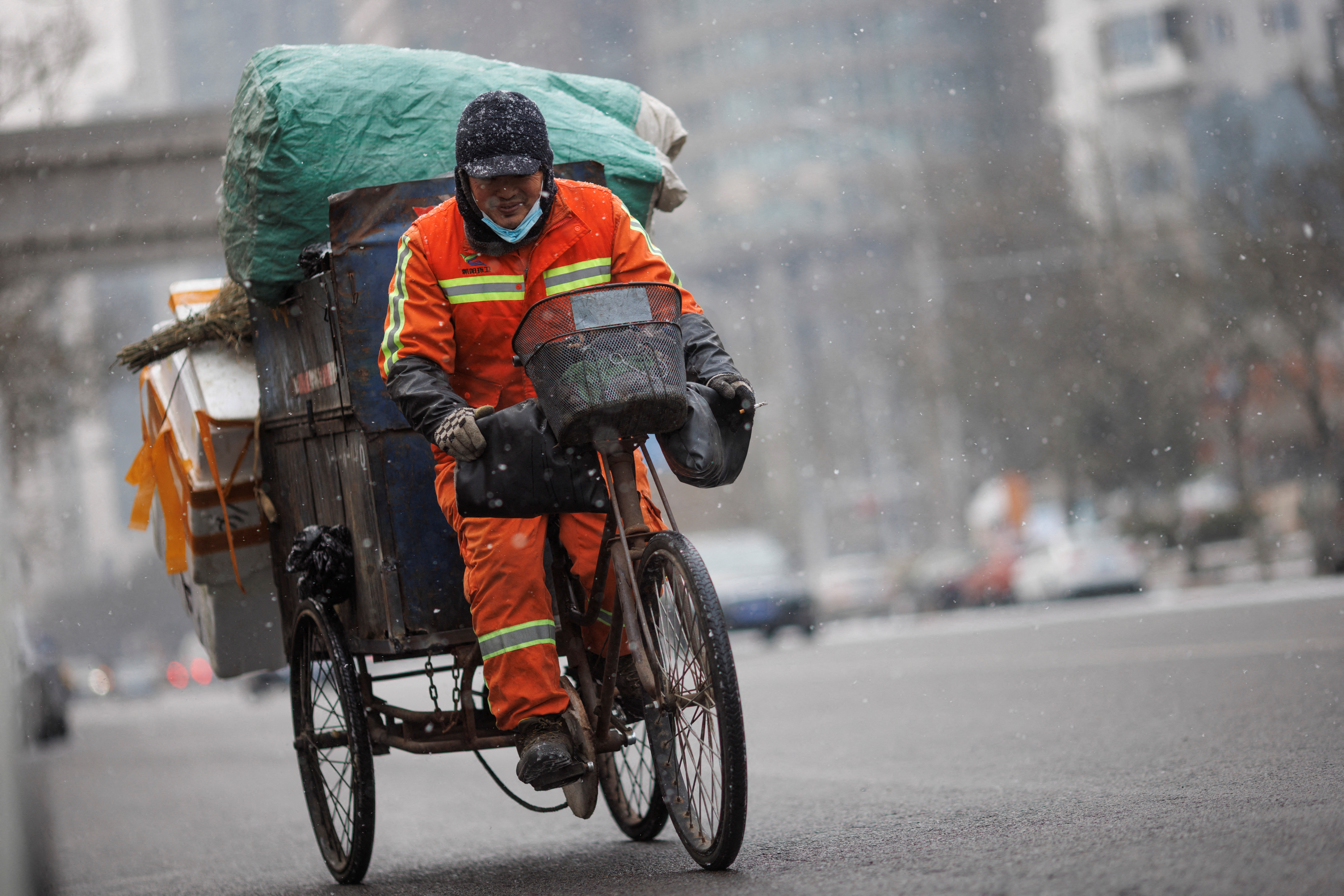 A municipal worker transports trash on a tricycle on a snowy morning as the coronavirus disease (COVID-19) continues in Beijing