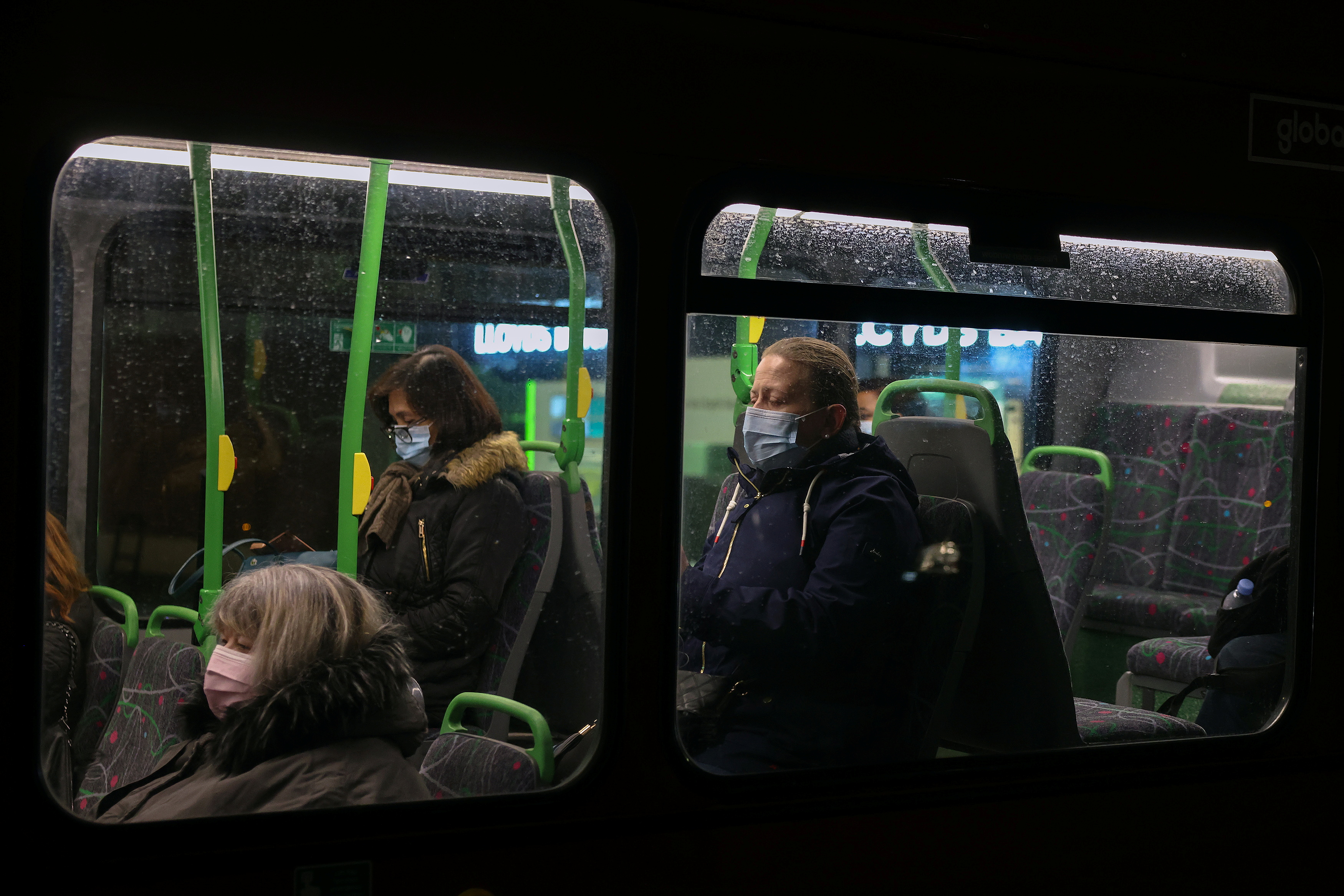 People wearing face masks sit on a bus in London, Britain November 26, 2021.    REUTERS/Kevin Coombs