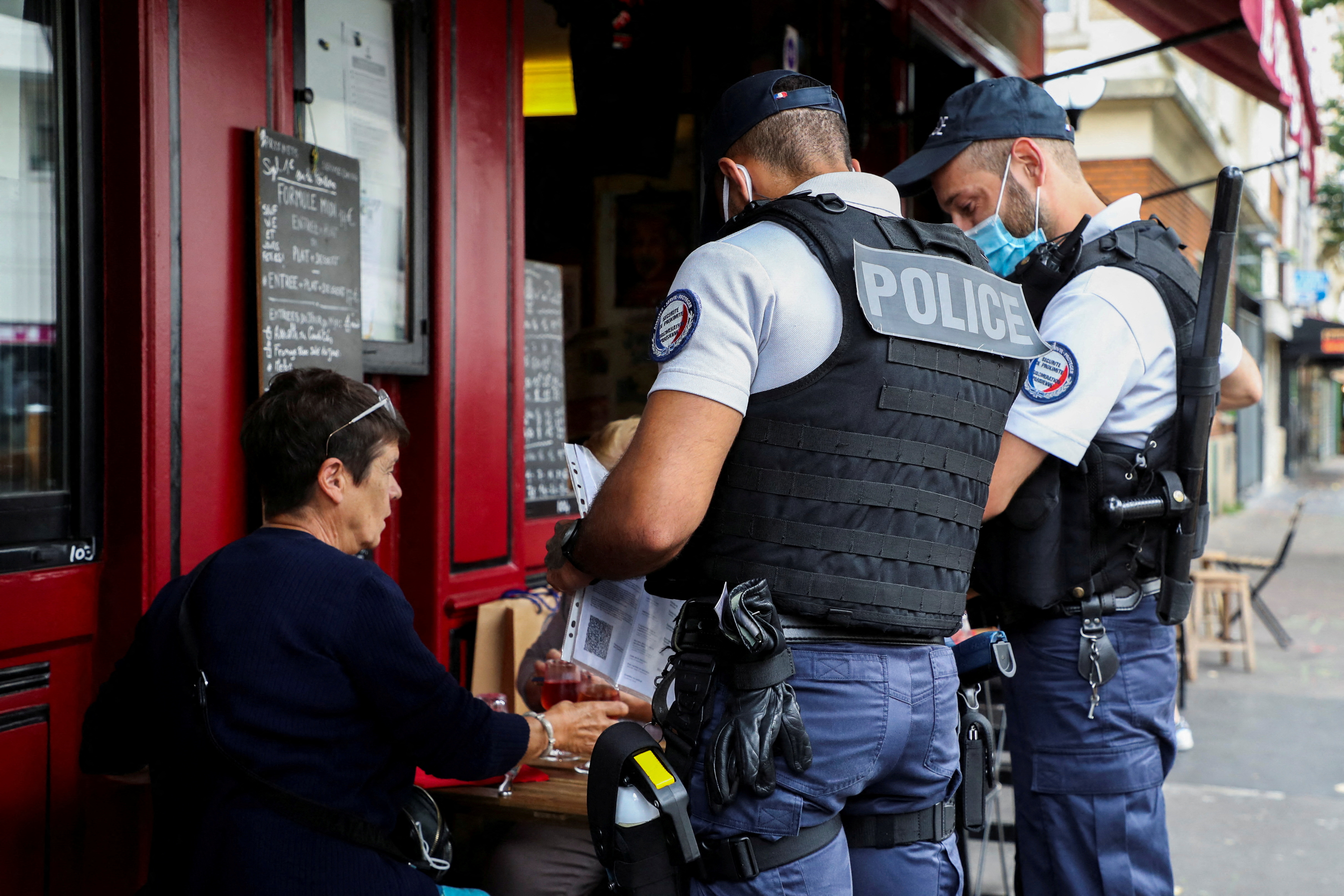 French police officers inspect the health pass compliance of a restaurant customer as checks on the implementation of the health pass are expected to be intensified in Paris, France, August 18, 2021. REUTERS/Sarah Meyssonnier/File Photo