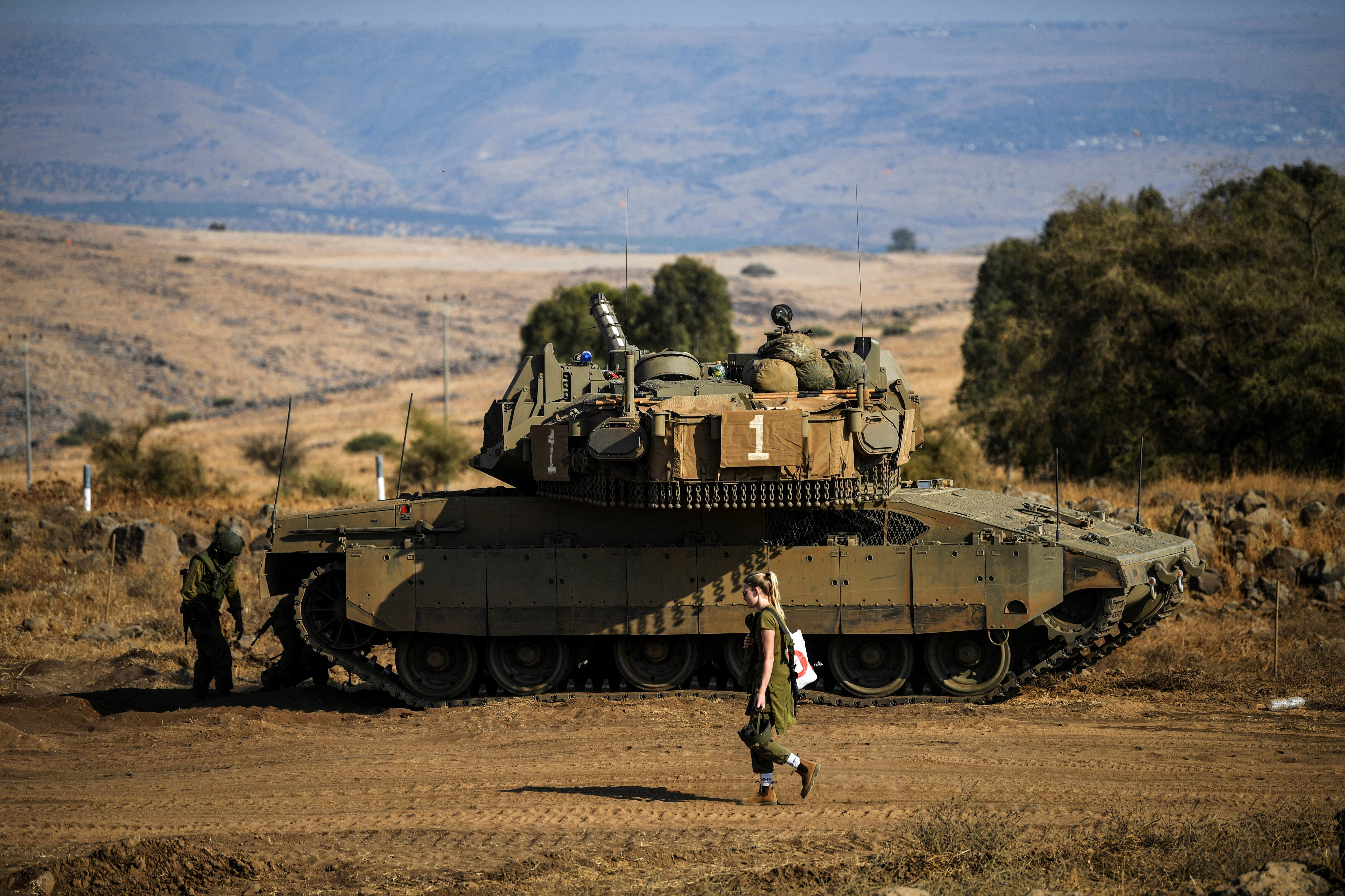 An Israeli soldier walks past a tank amid heightened tensions between Israel and Lebanon, as seen from the border with Lebanon in northern Israel