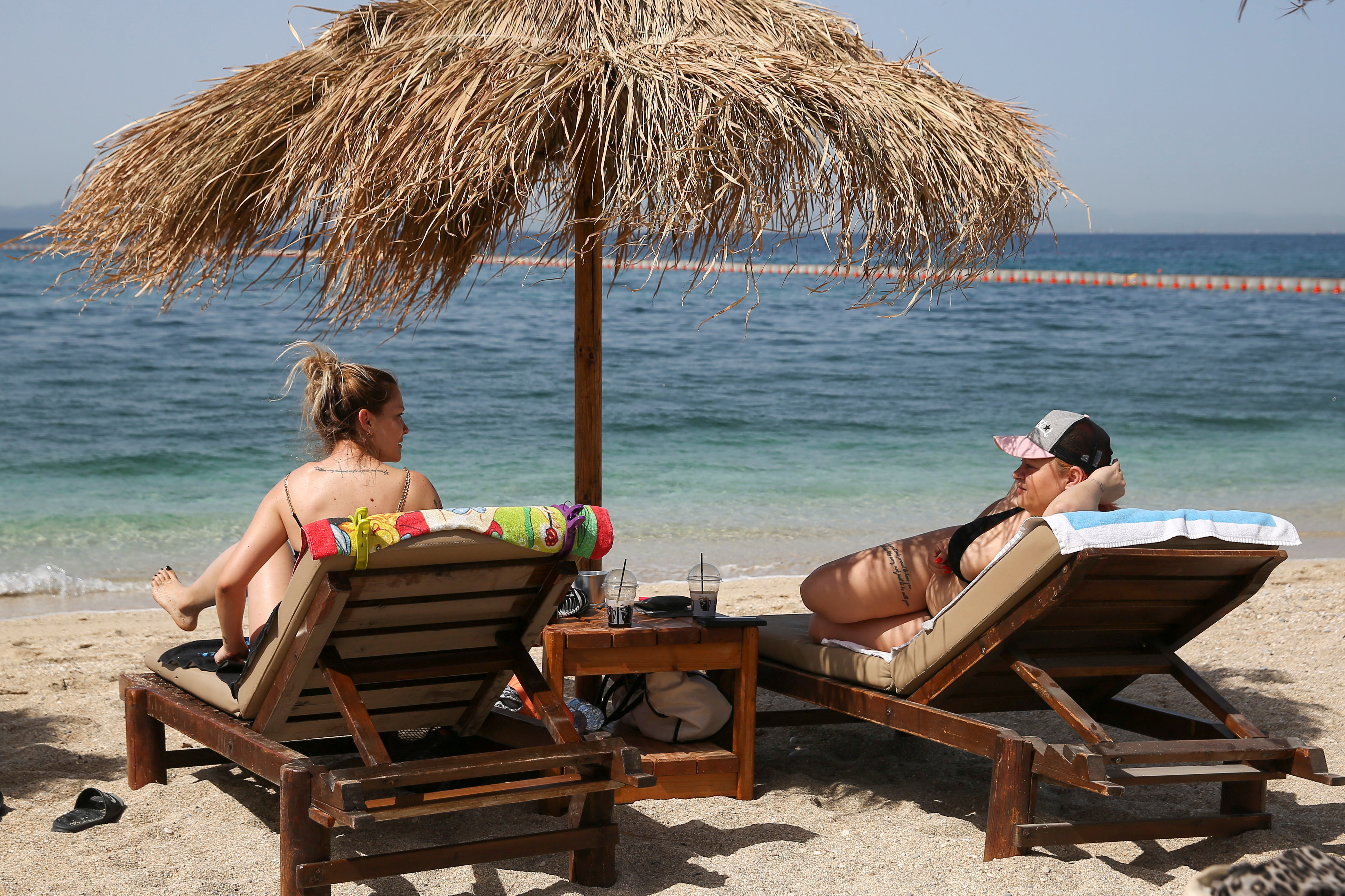 As pessoas aproveitam o sol durante a reabertura oficial das praias ao público, após o abrandamento das medidas contra a propagação da doença coronavírus (COVID-19), em Atenas, Grécia, 8 de maio de 2021. REUTERS / Costas Baltas