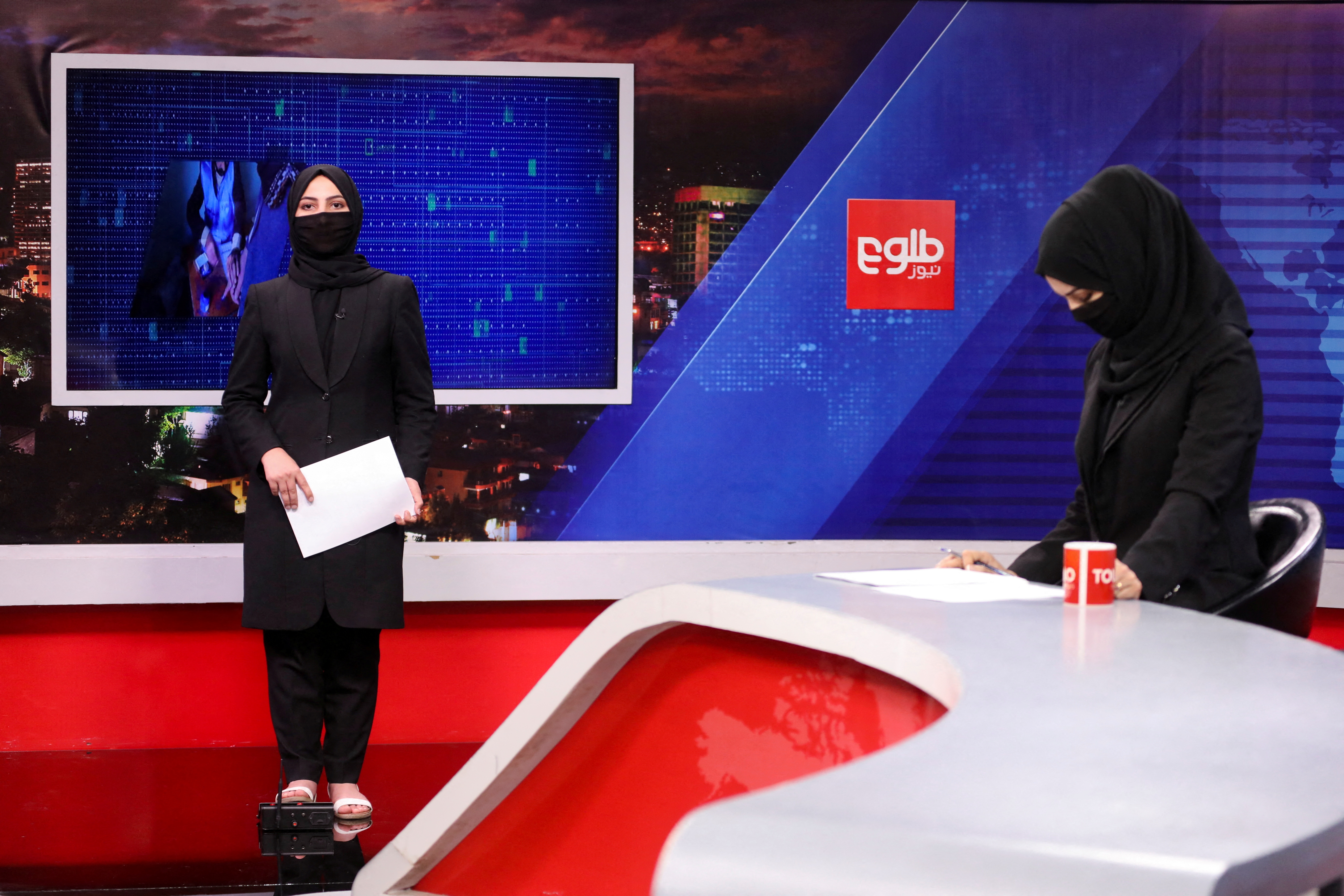 Female presenters for Tolo News, Sonia Niazi and Khatereh Ahmadi, while covering their face, work in a newsroom at Tolo TV station in Kabul