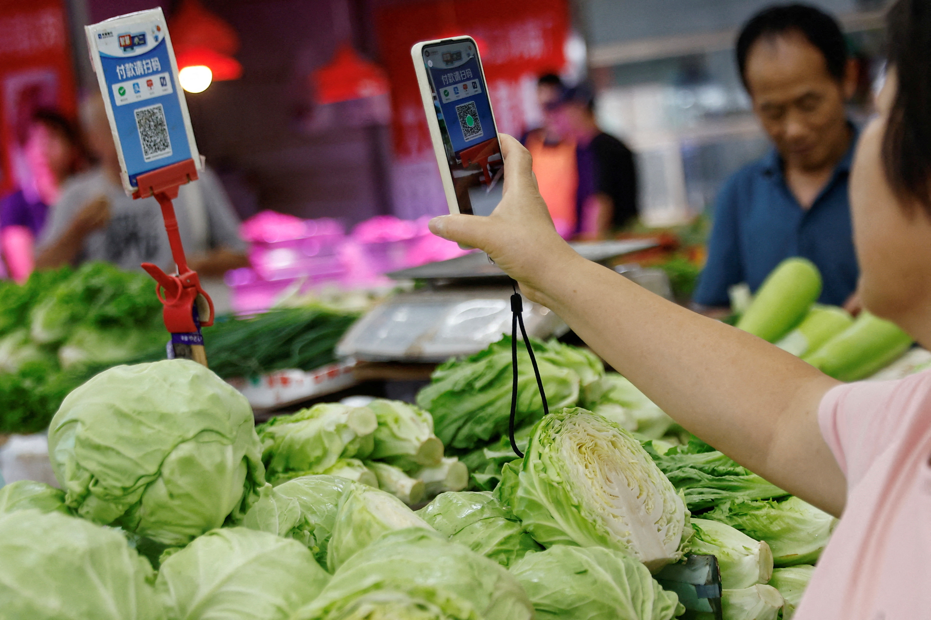 Customer scans a QR code to pay for vegetables at a morning market in Beijing