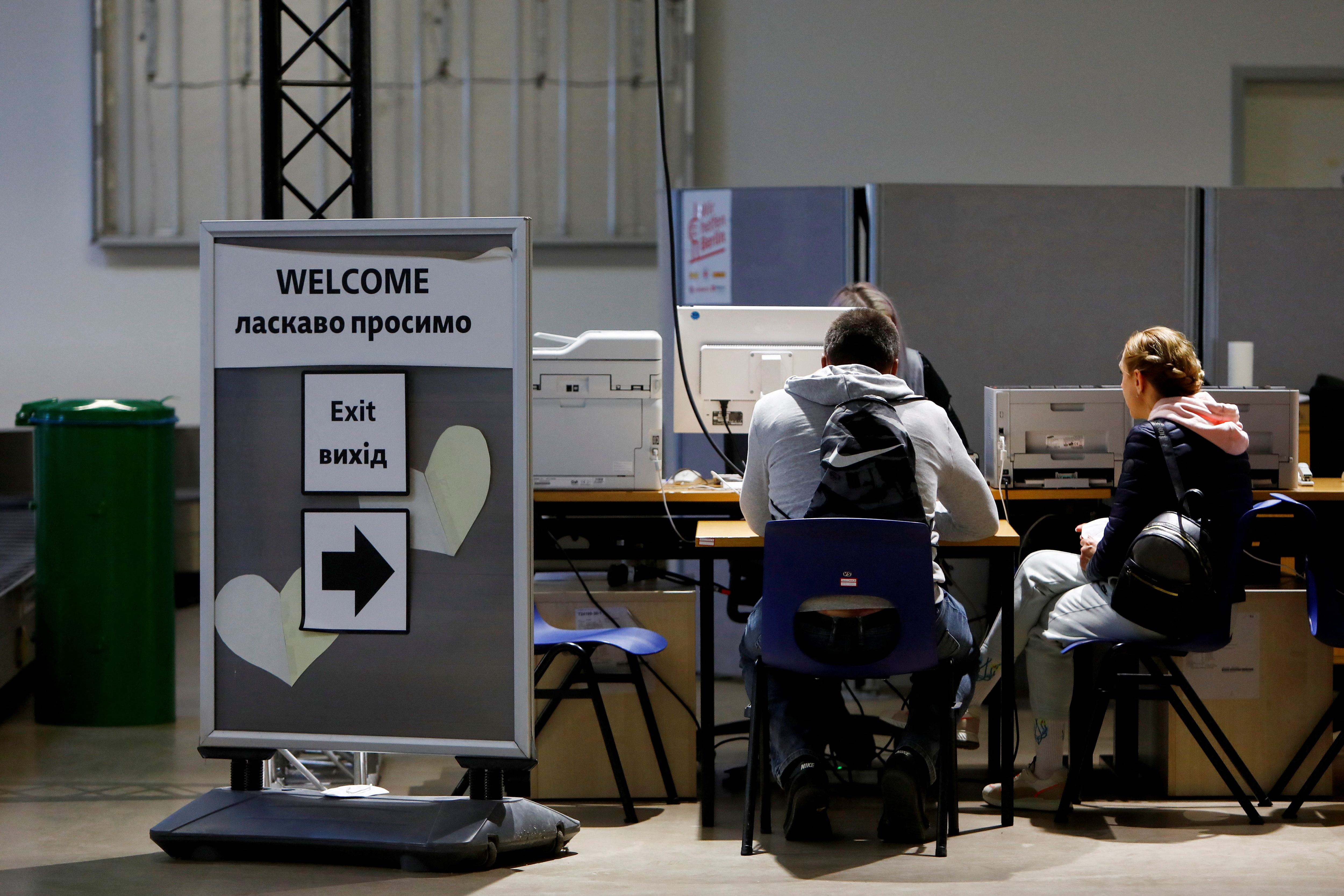 People sit at the registration as they arrive at the accommodation centre for refugees from Ukraine at the former Tegel airport in Berlin