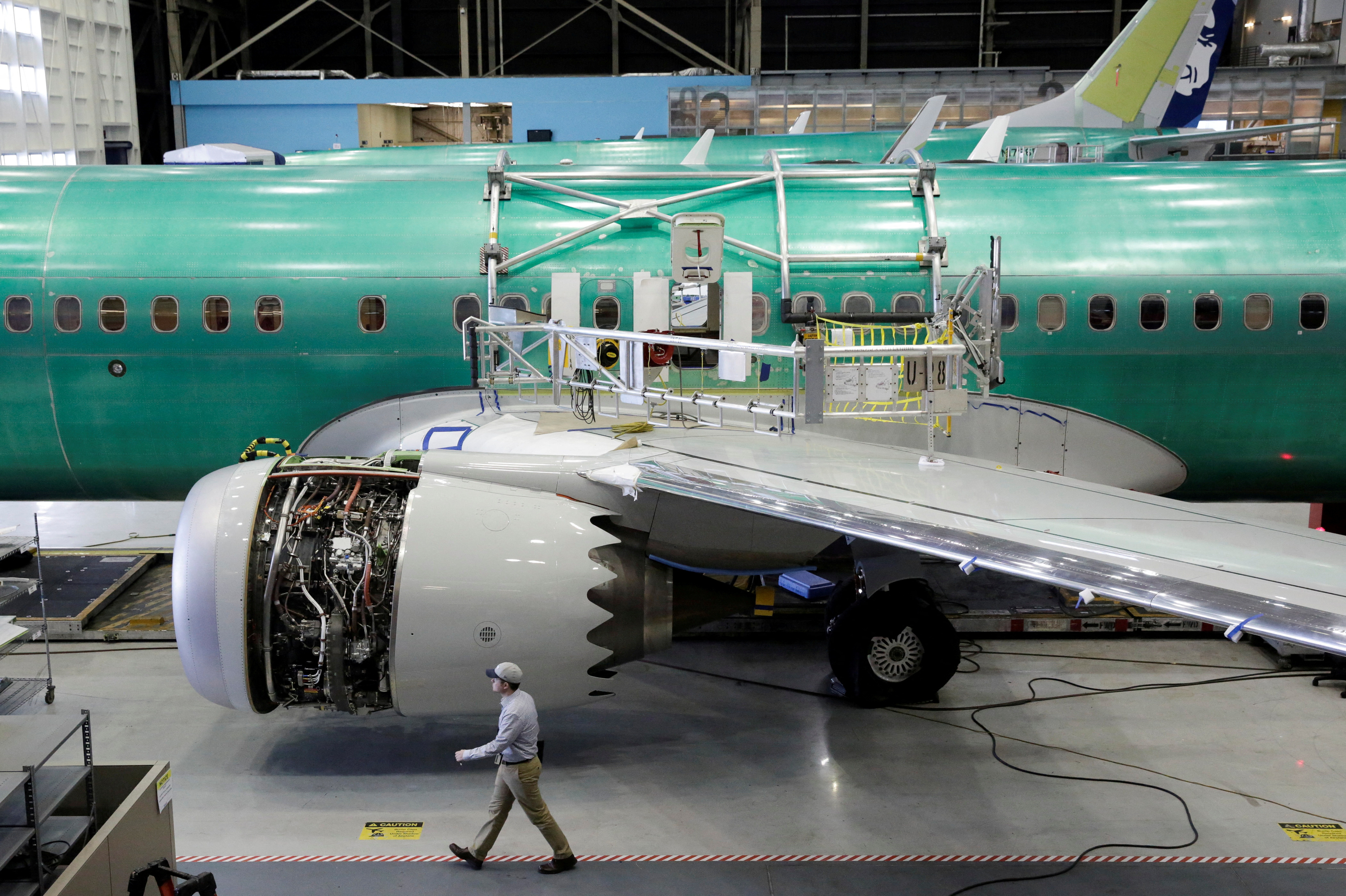 A worker walks past Boeing's 737 MAX-9 under construction at their production facility in Renton, Washington
