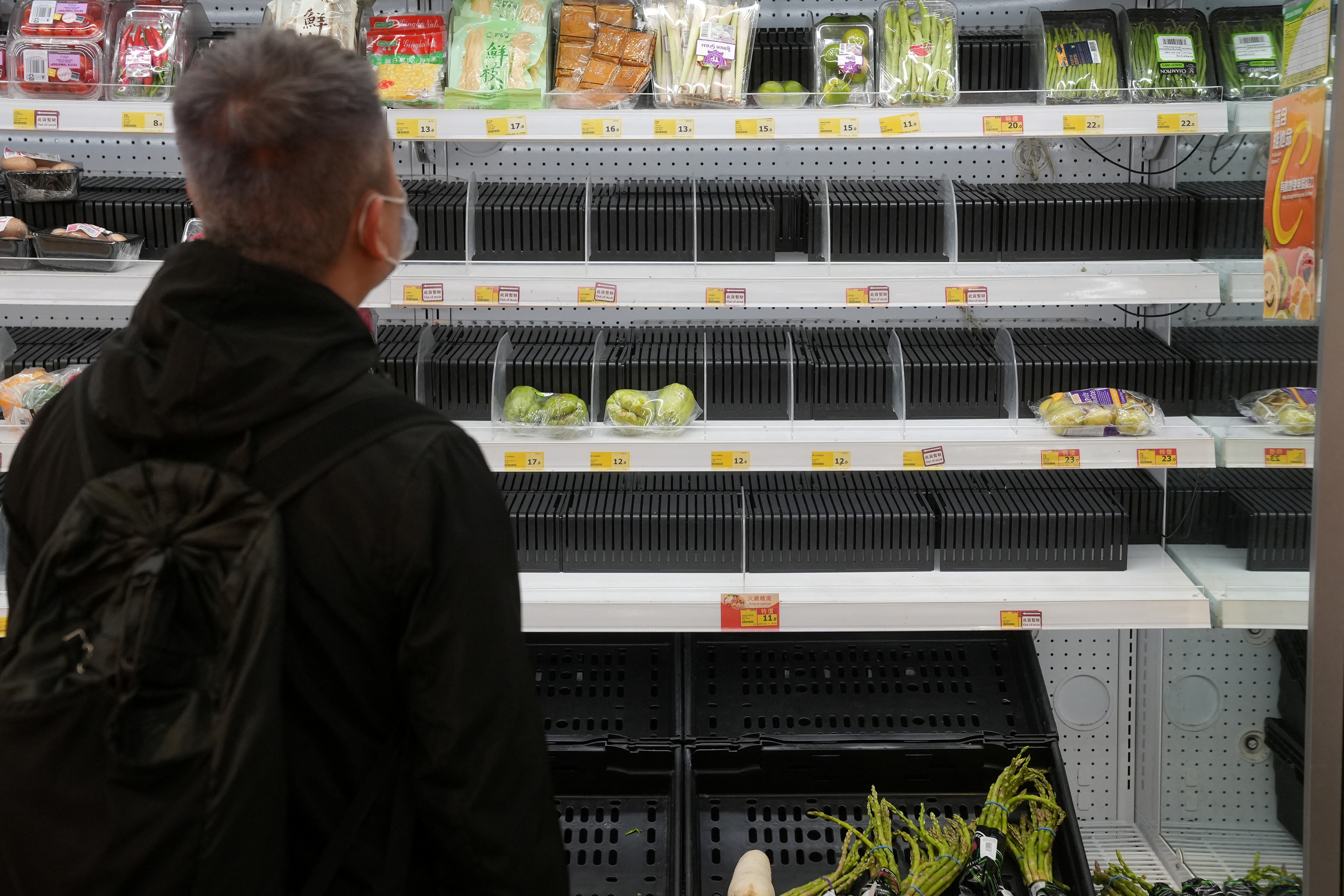 Customer wearing a face mask shops in front of partially empty shelves at a supermarket, following the outbreak of the coronavirus disease (COVID-19), at Sha Tin district