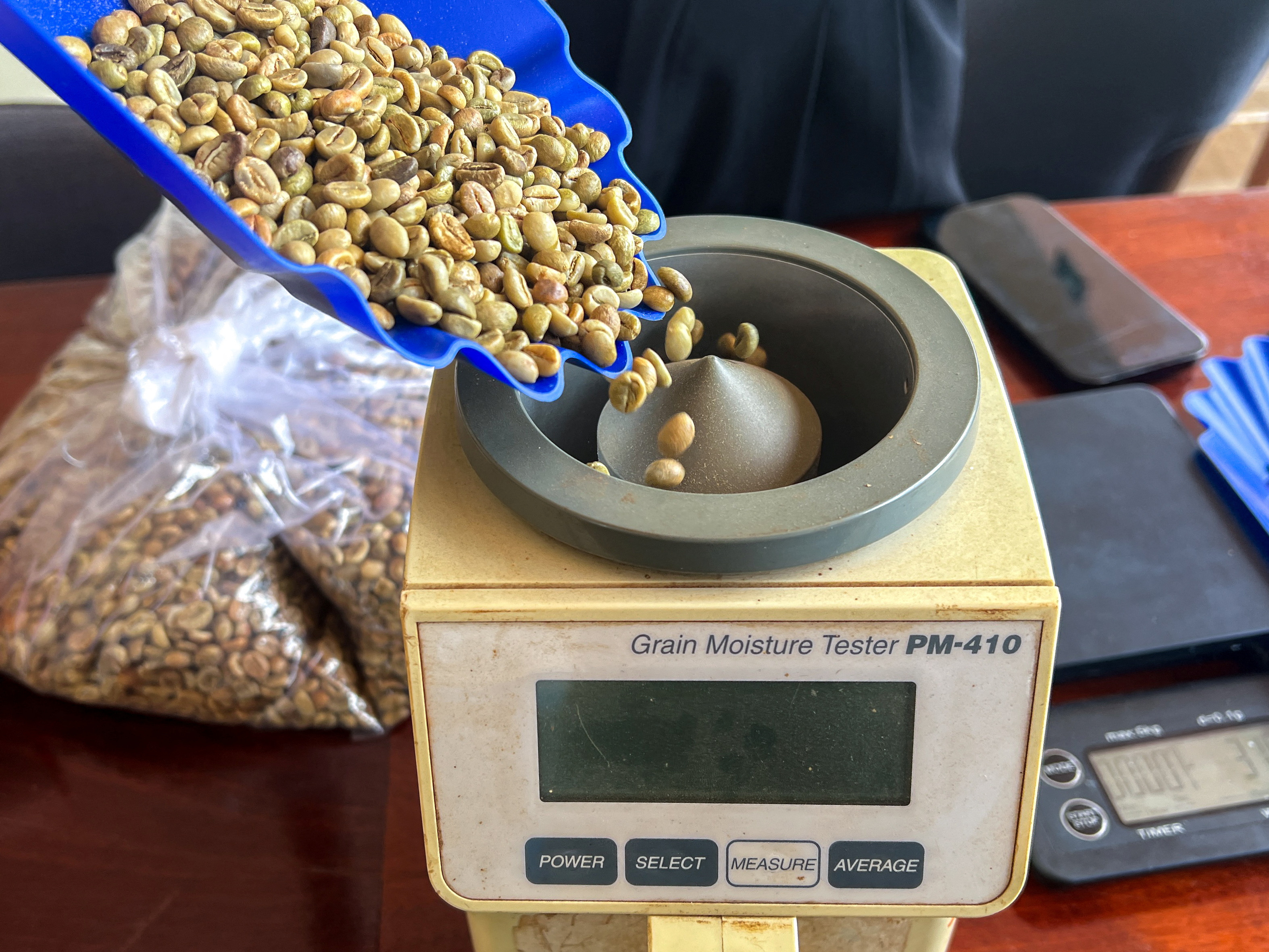 A worker pours coffee beans into a moisture tester machine, in Pleiku