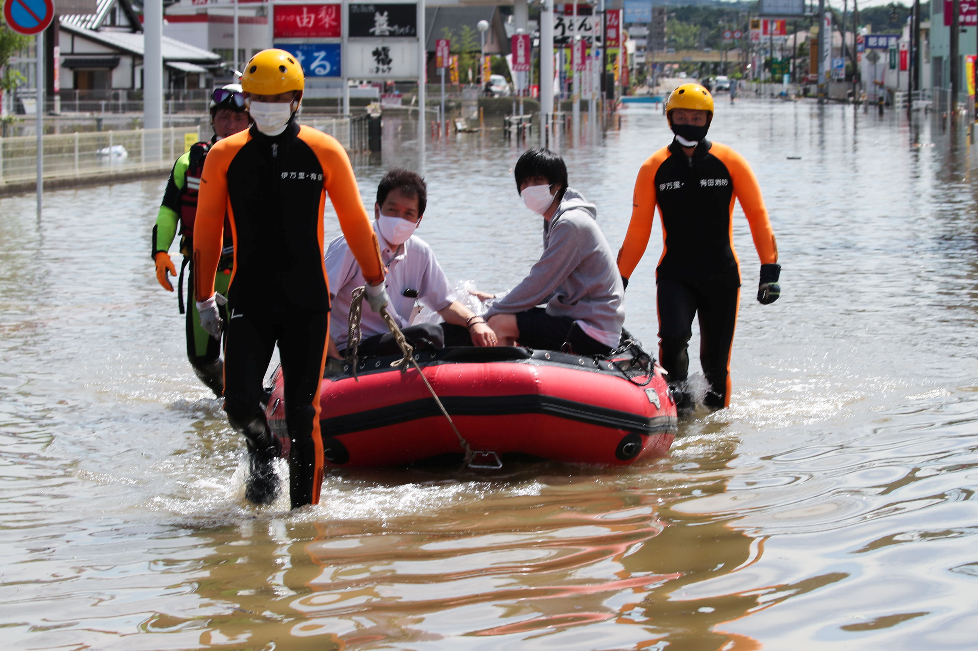 Rescue workers transport people using a boat along a flooded street in Takeo, Saga Prefecture, western Japan